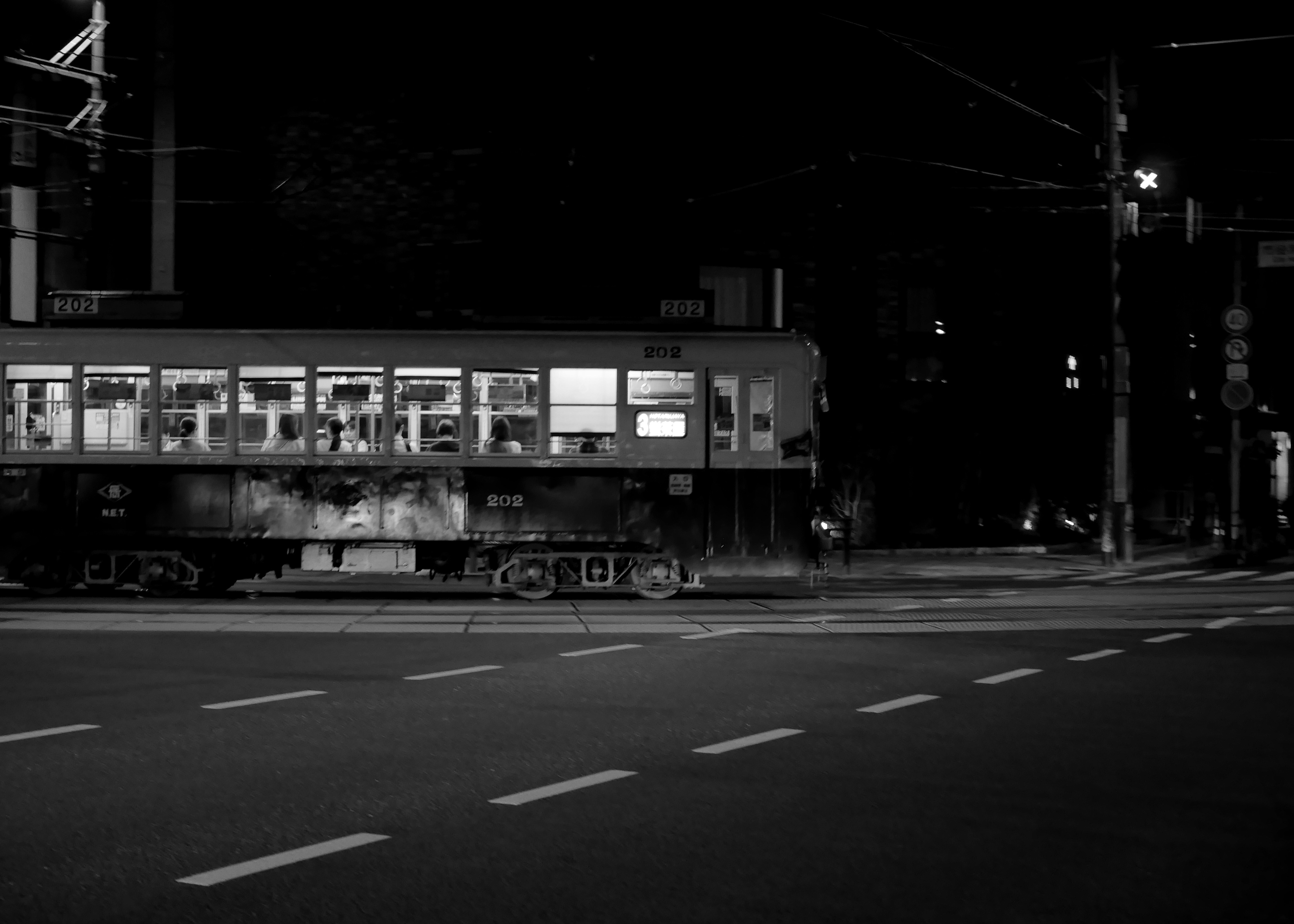 Vagón de tren iluminado en una calle oscura por la noche.