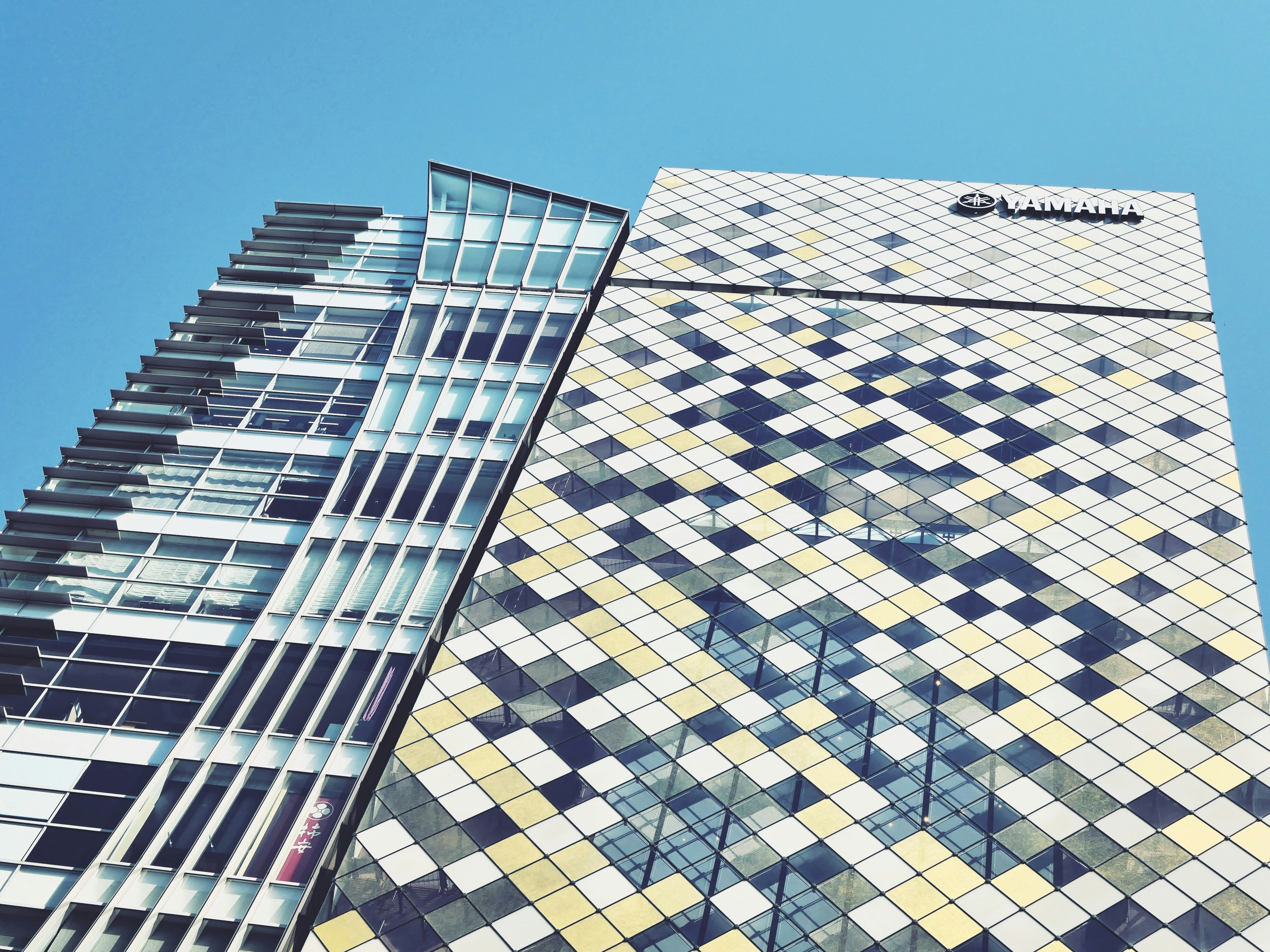 Edificios modernos con fachadas de cristal y mosaico contra cielo azul.