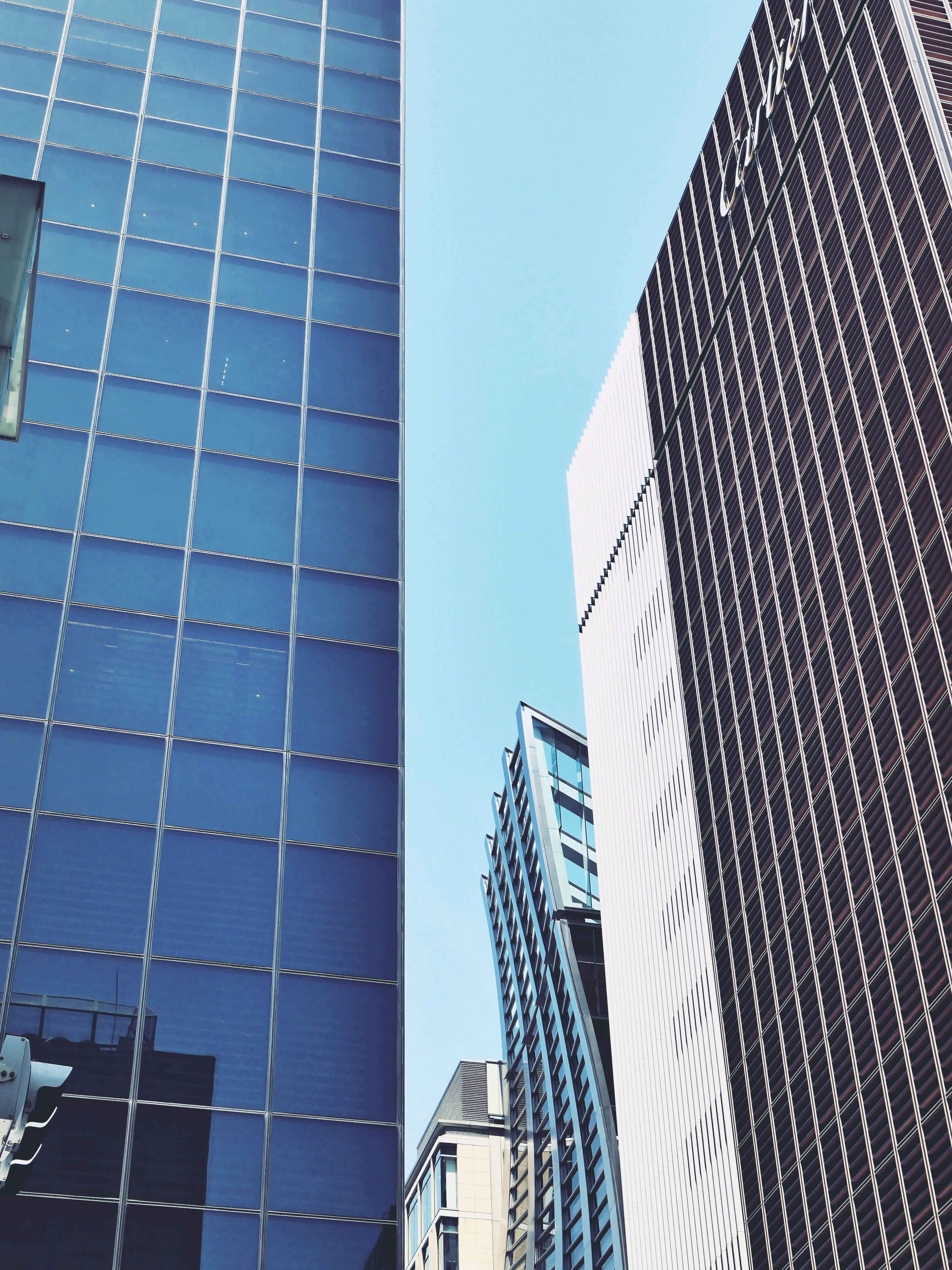 Edificios modernos altos con fachadas de cristal contra un cielo azul.
