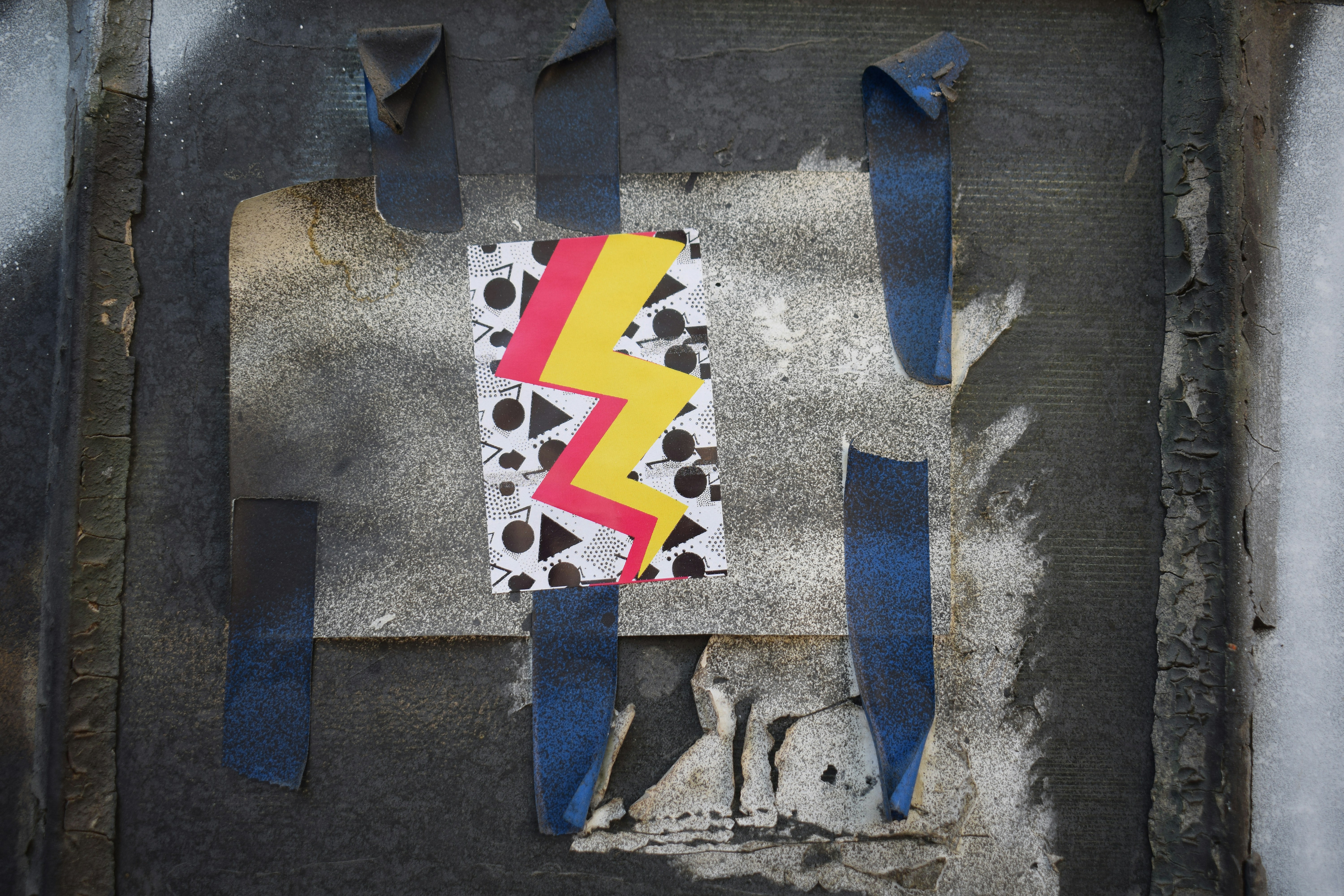 Lightning bolt design taped to a dark, distressed surface.
