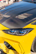 Yellow car with carbon fiber hood and modern headlights.