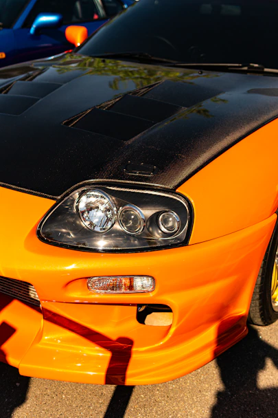 An orange sports car with a black hood and headlights.