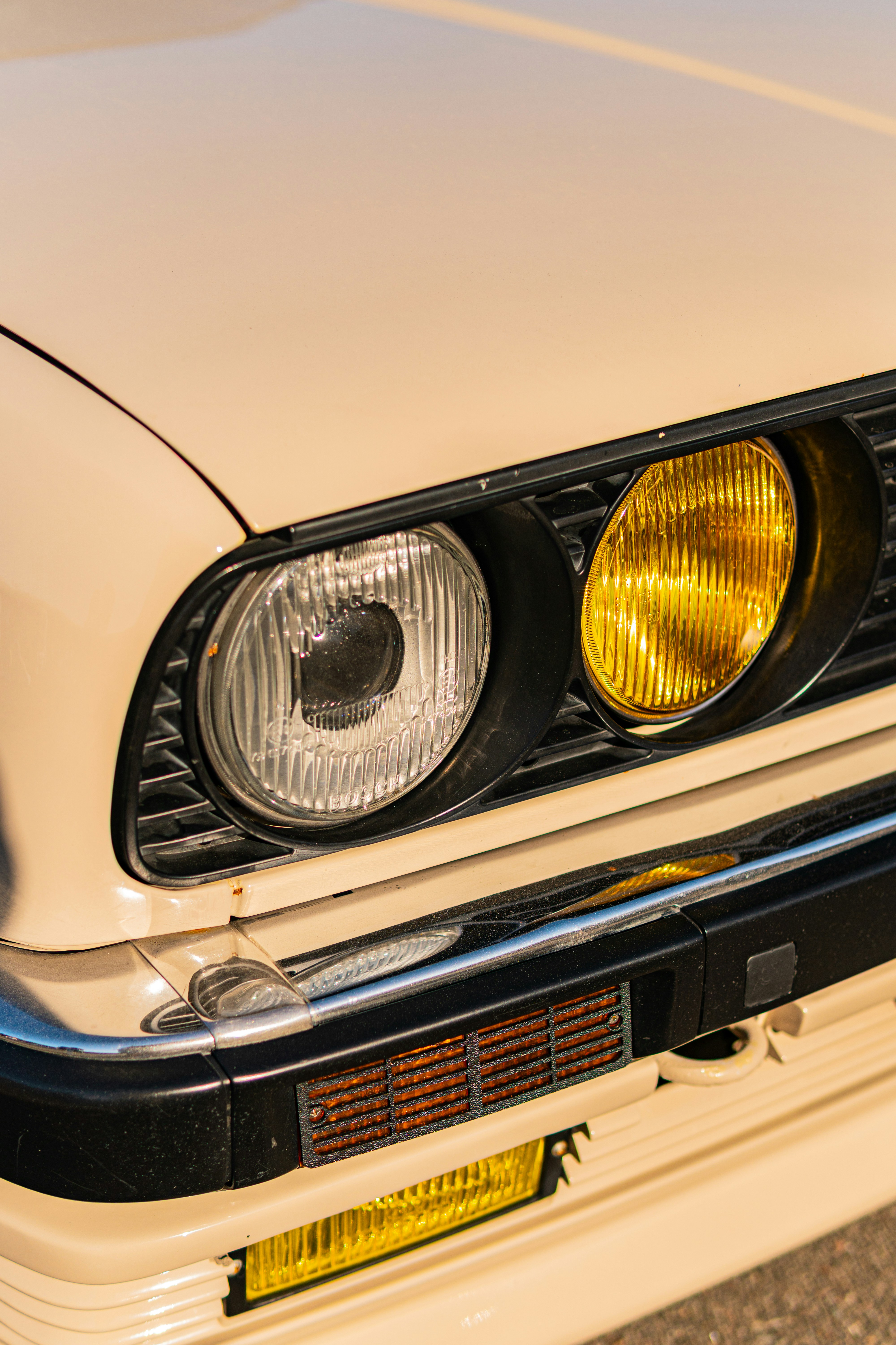 Beige car front with clear and yellow headlights