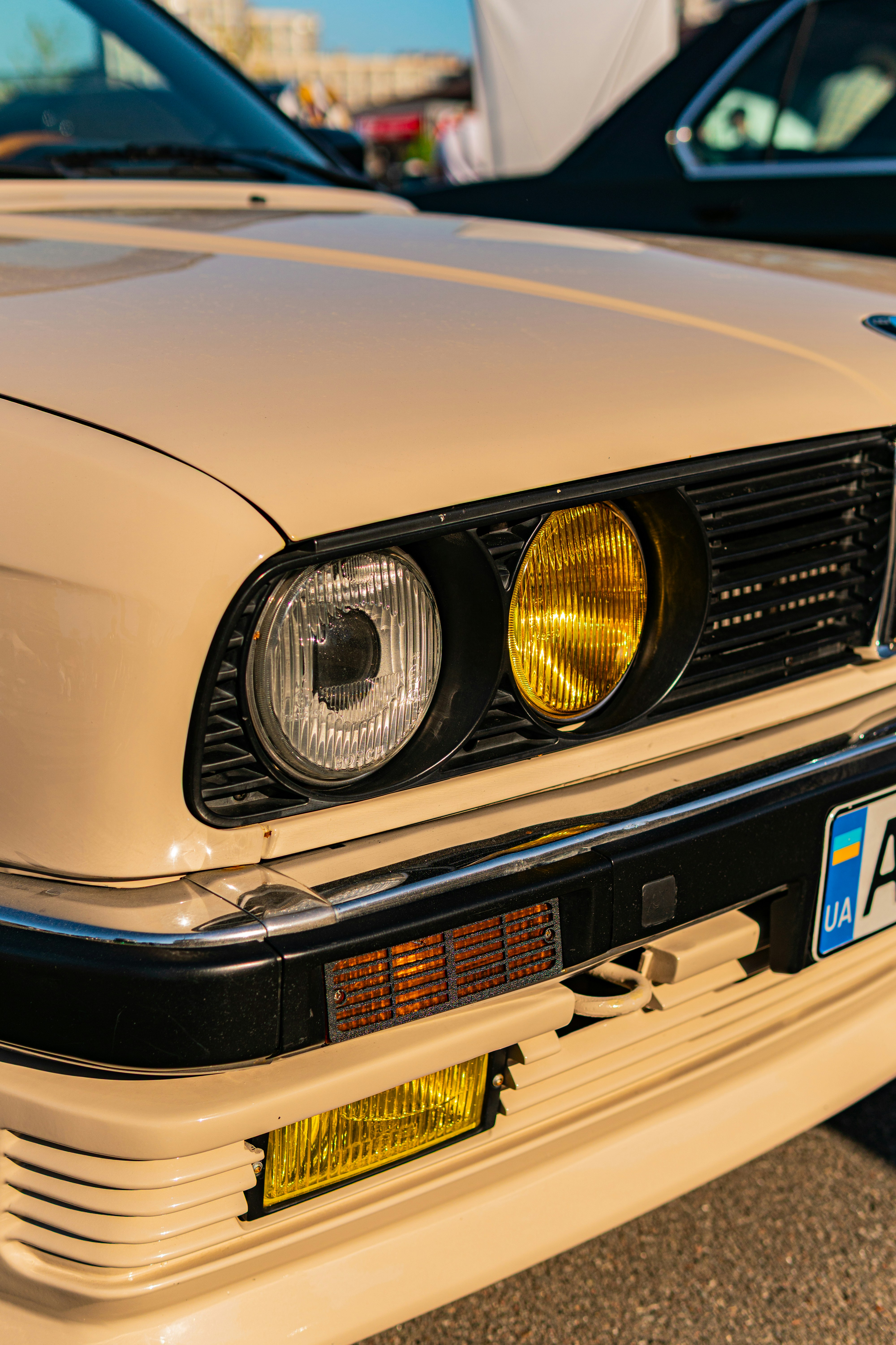 Classic beige car's front with distinct yellow and clear headlights