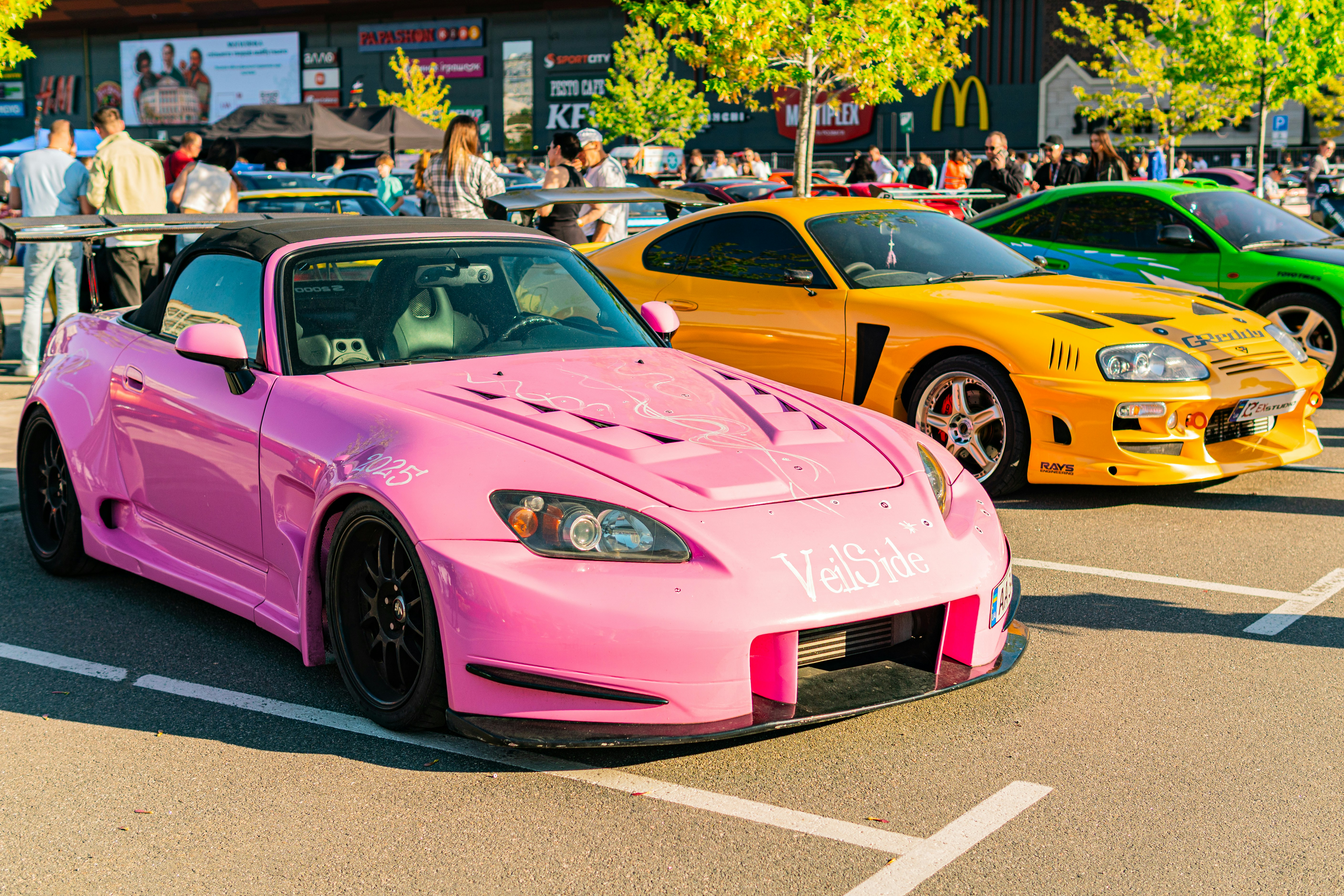 Pink, yellow, and green custom sports cars parked outdoors