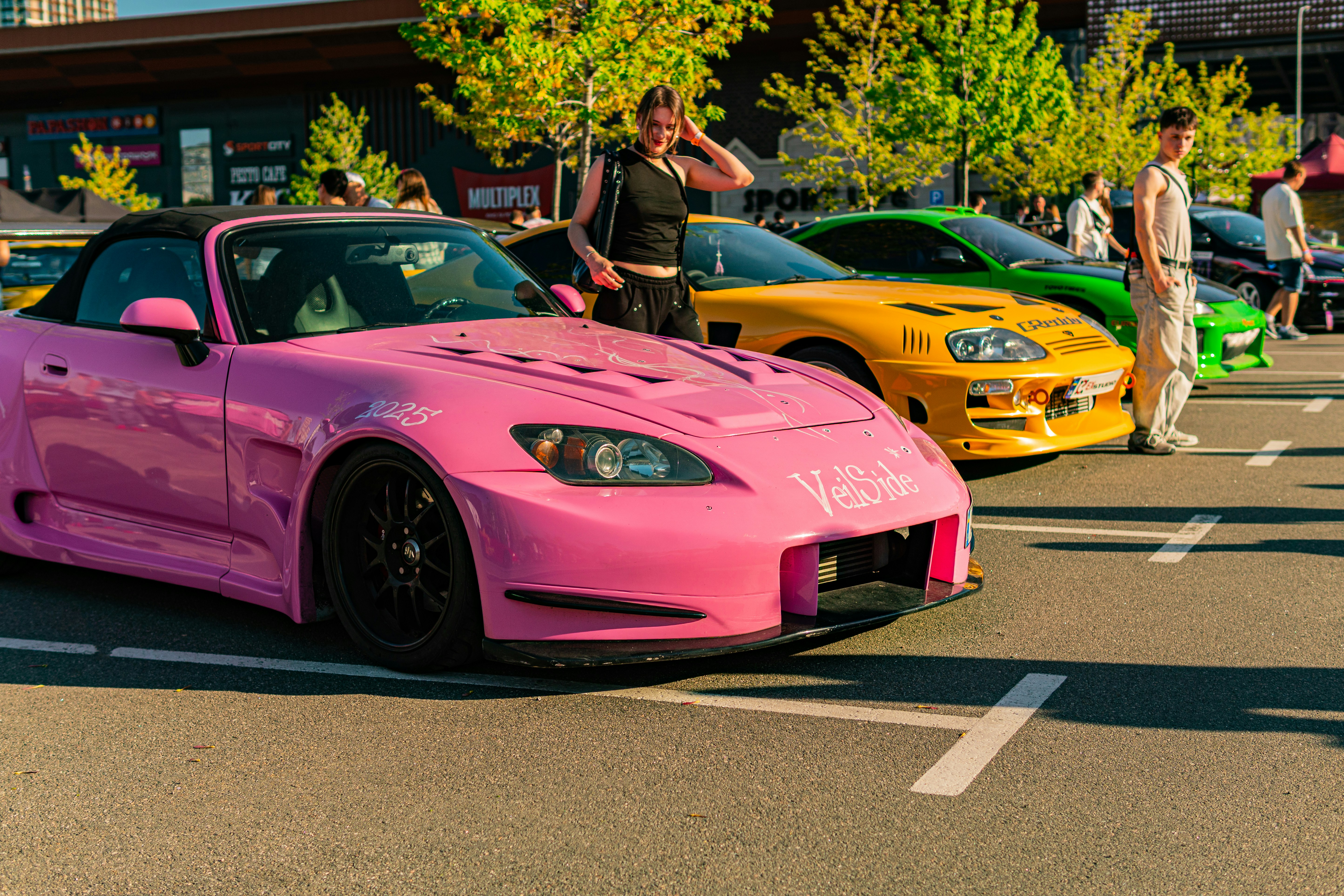 A vibrant pink sports car at an outdoor car meet