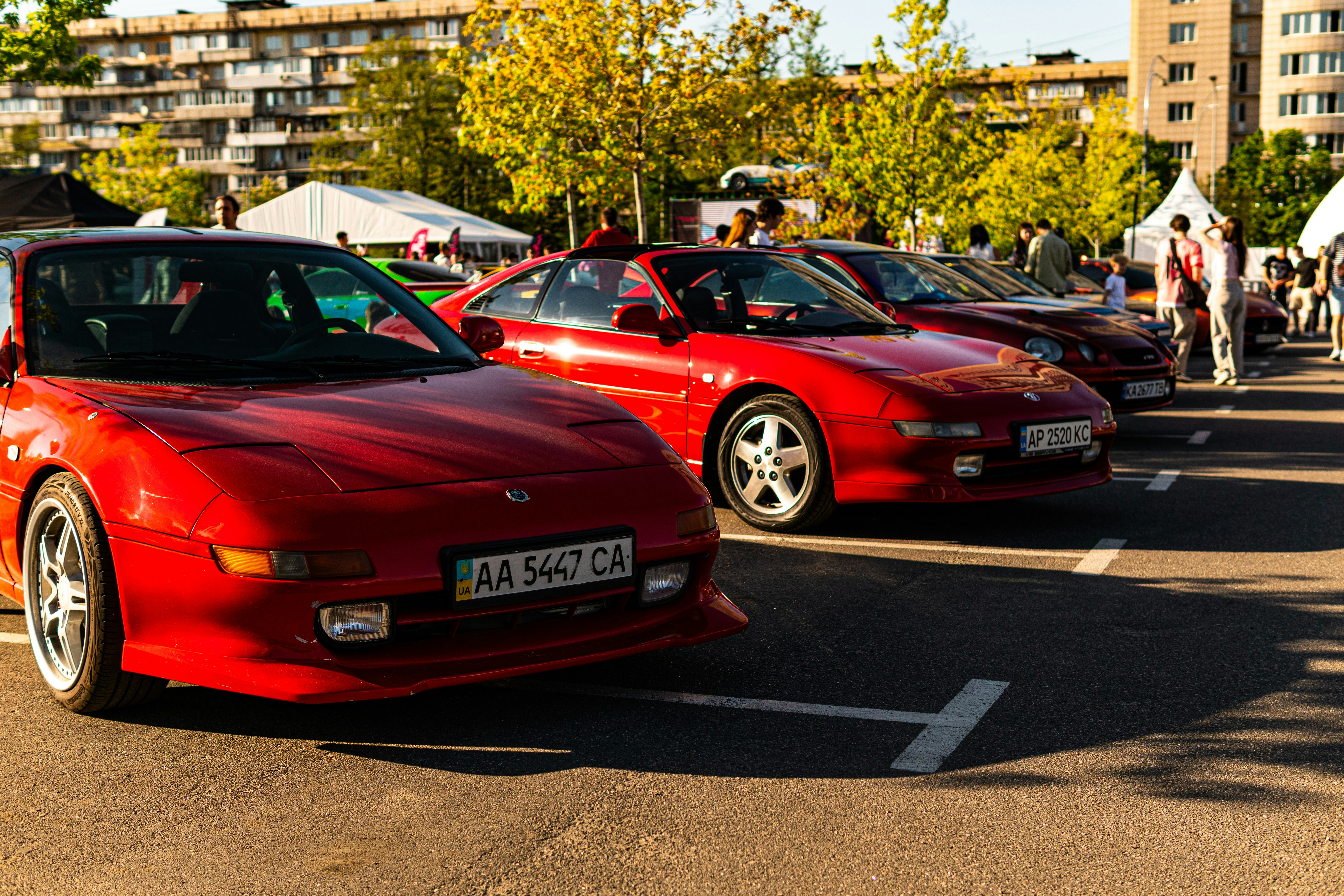 Several red sports cars parked outdoors at a car show