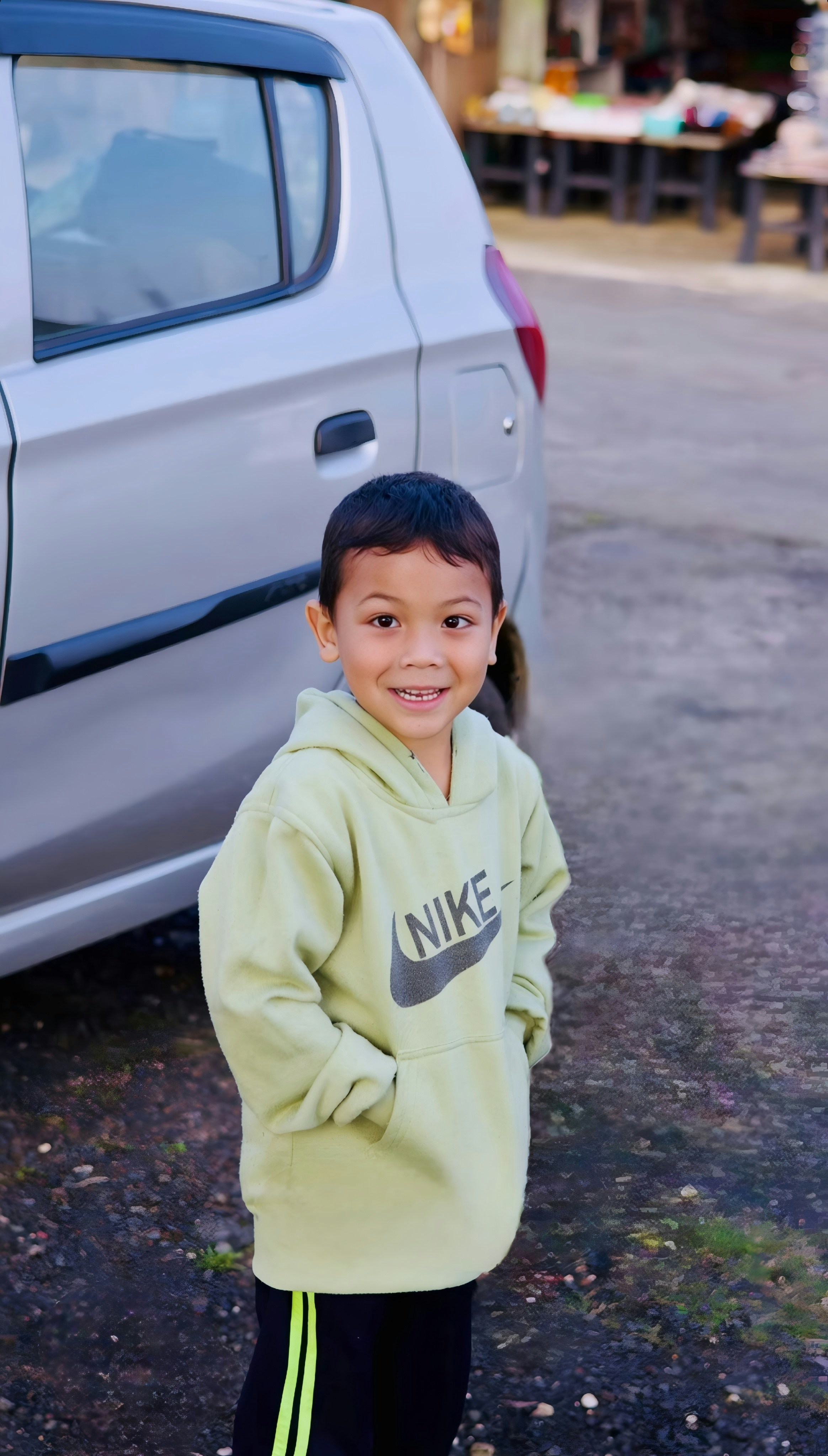 Un ragazzino sorridente con una felpa verde Nike.