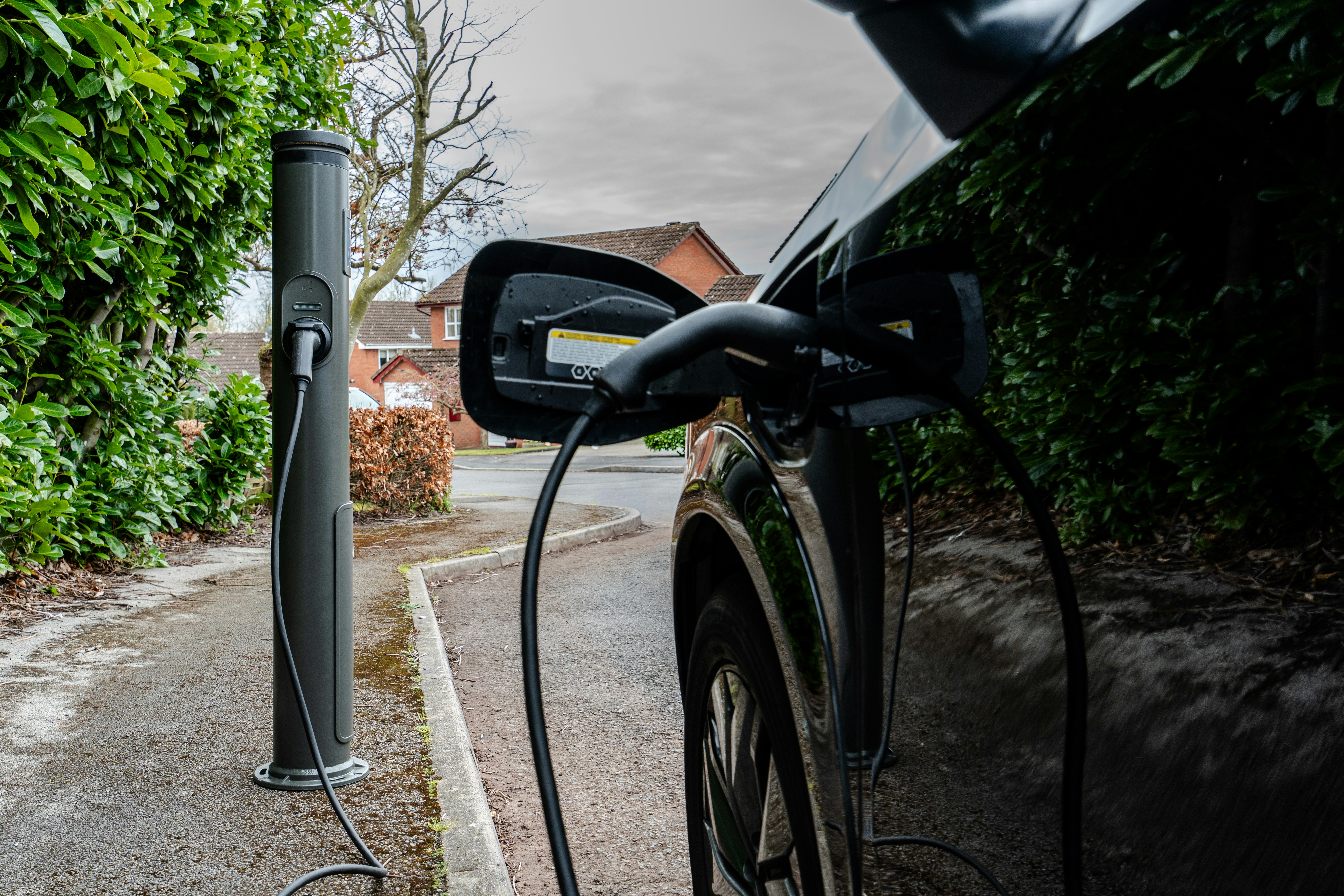electric vehicle home charging station - Electric car plugged into a charging station outdoors.