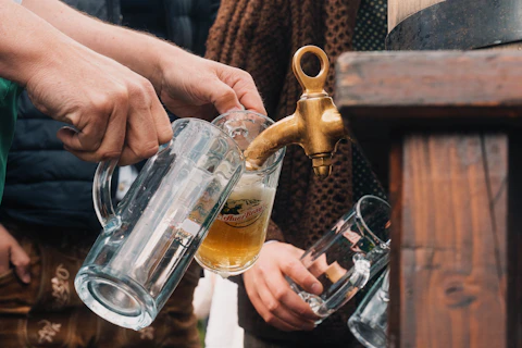 Hands pouring beer from a tap into a glass mug