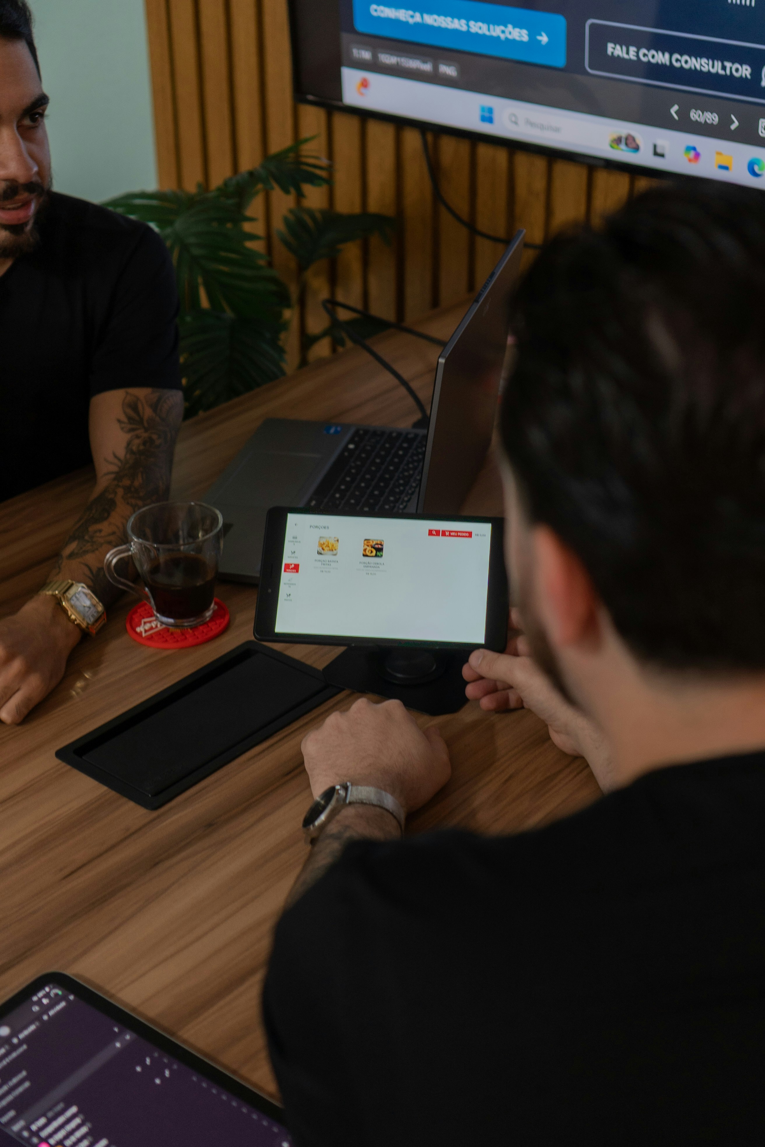 Deux hommes collaborant, l’un regardant une tablette.