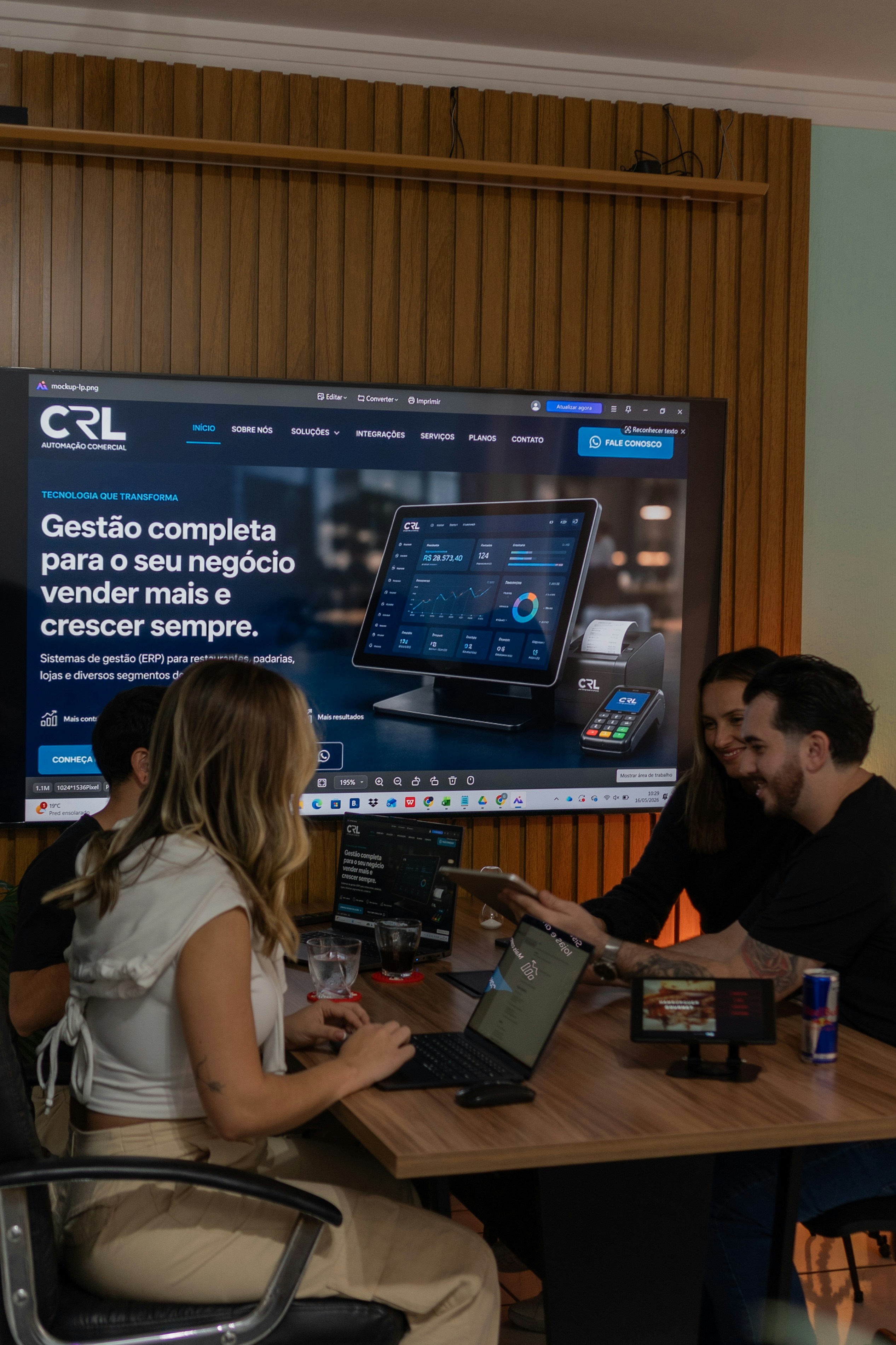 Colleagues collaborating around a table with a large screen display.