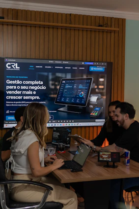 Colleagues collaborating around a table with a large screen display.