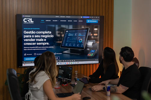 Three colleagues viewing a business presentation on a large screen.