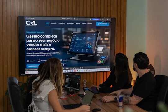Three colleagues viewing a business presentation on a large screen.