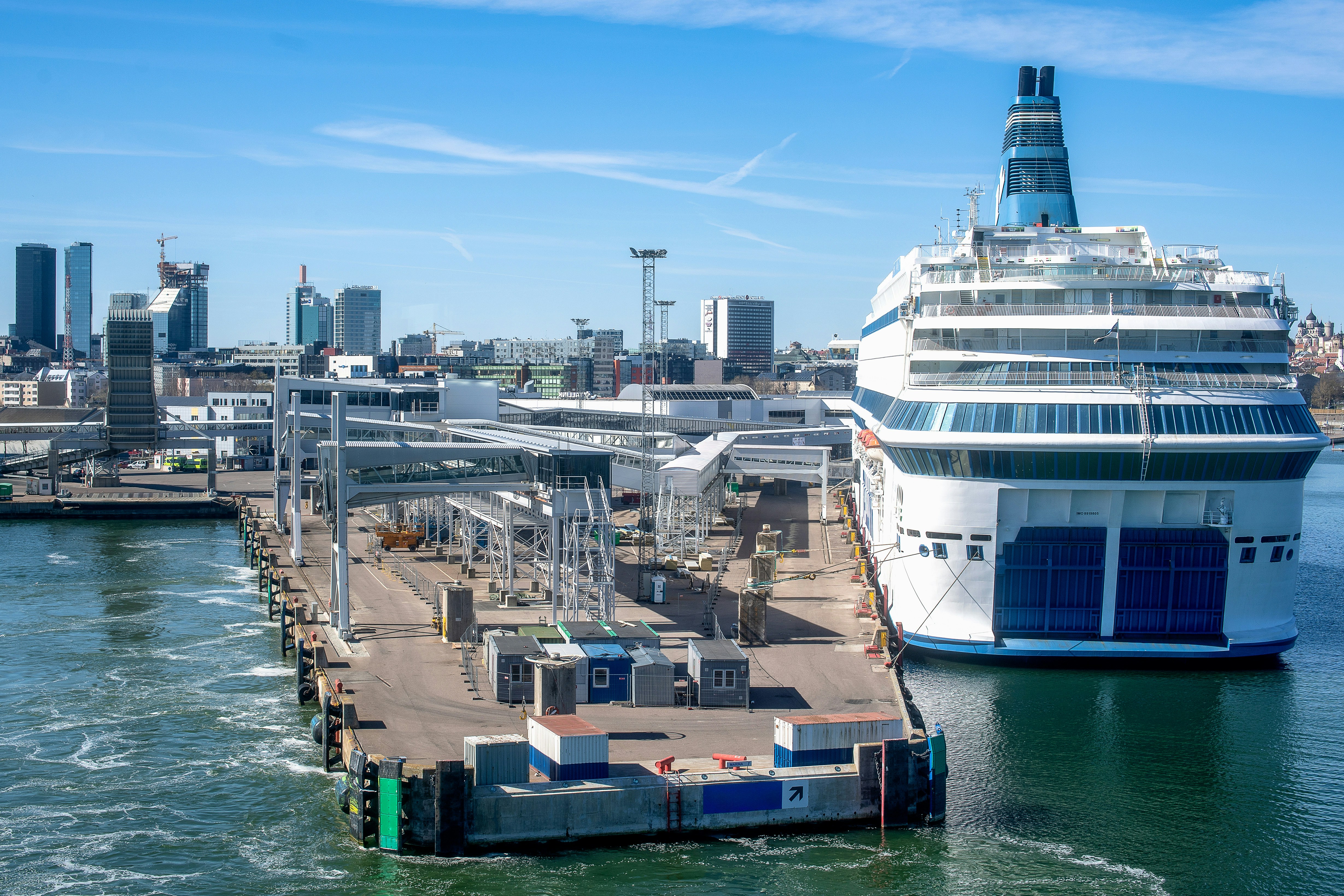 White ferry docked at a city port with urban skyline.