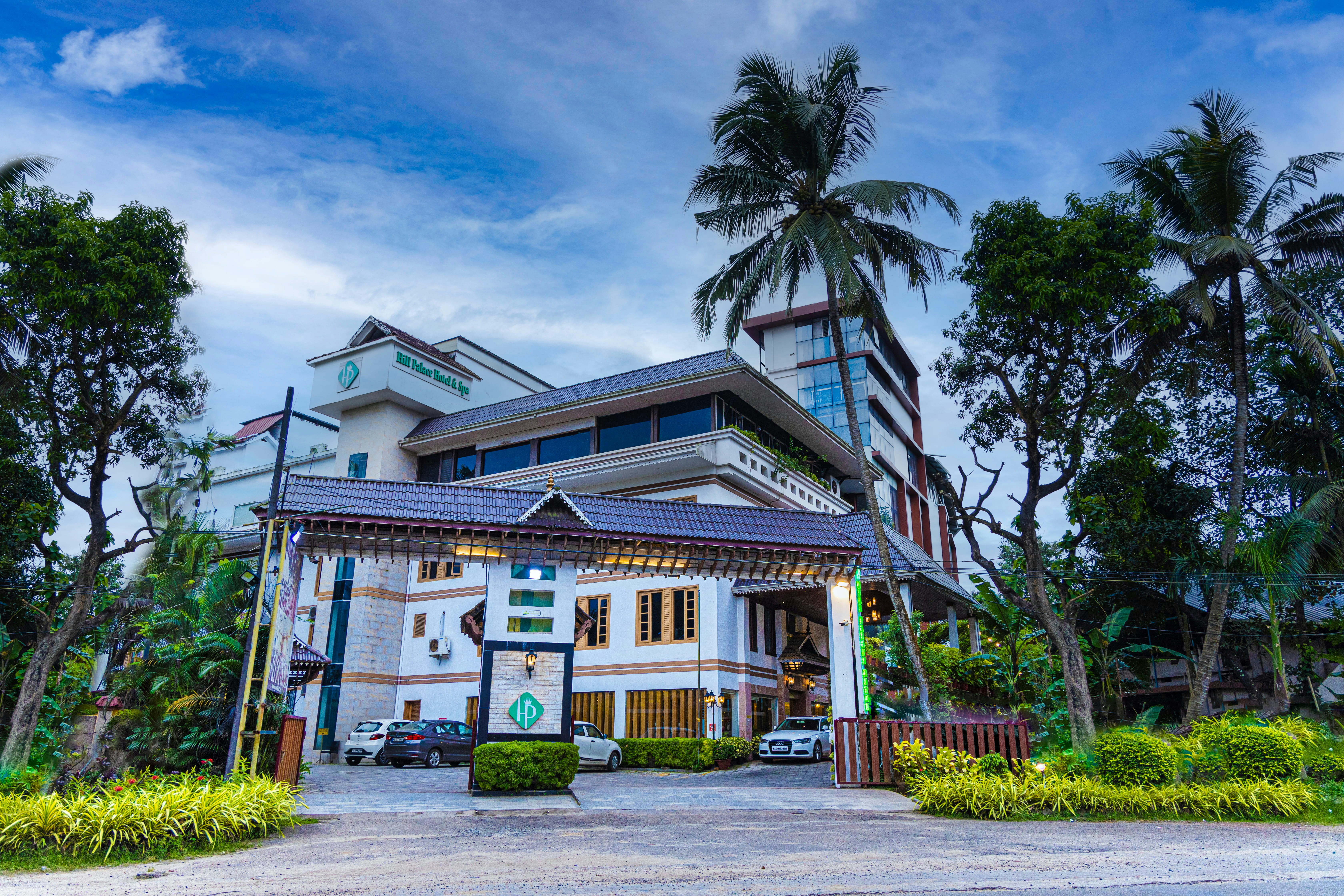 Modern hotel with traditional roofs surrounded by tropical palm trees.