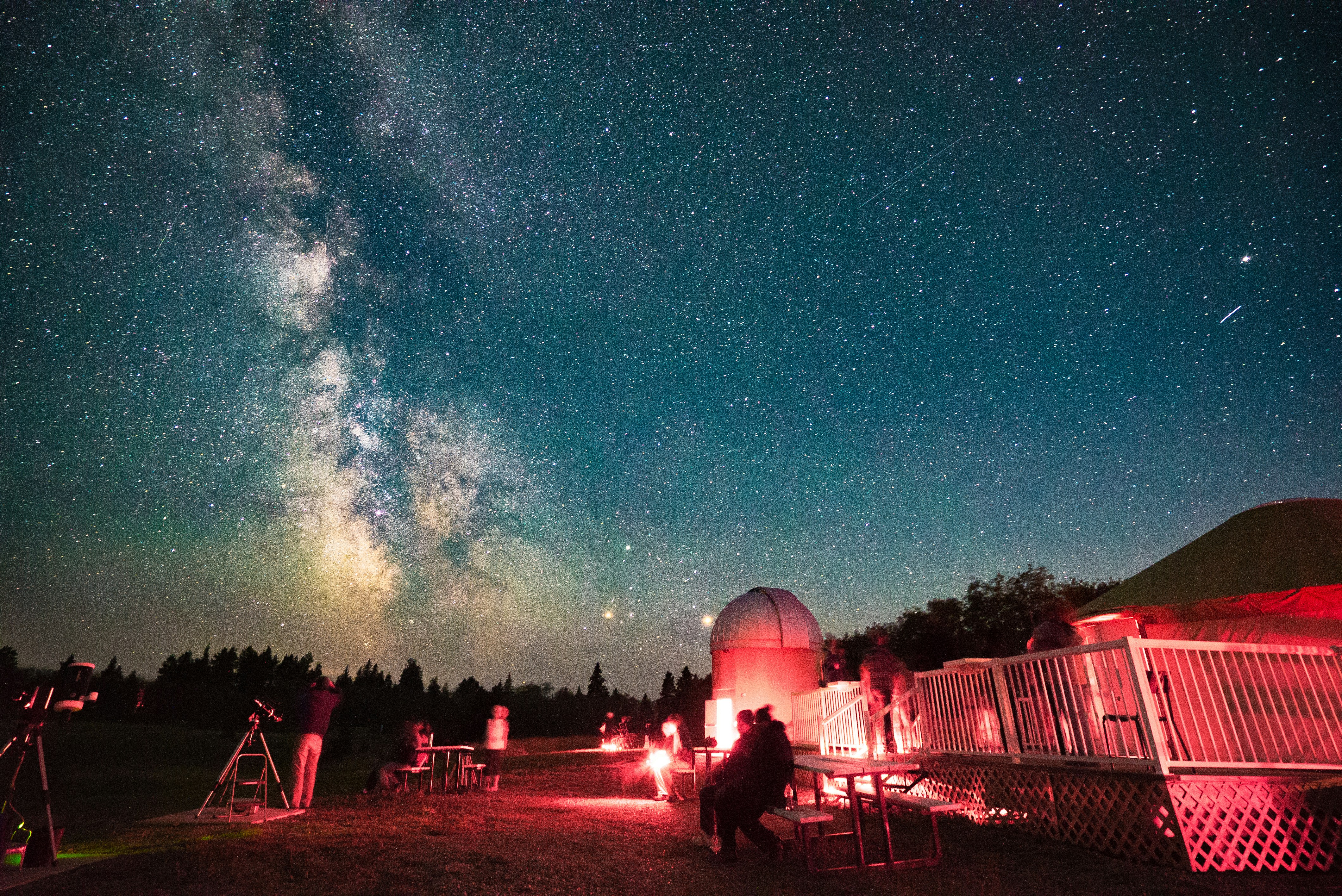 Night sky with milky way, observatory, and people stargazing.
