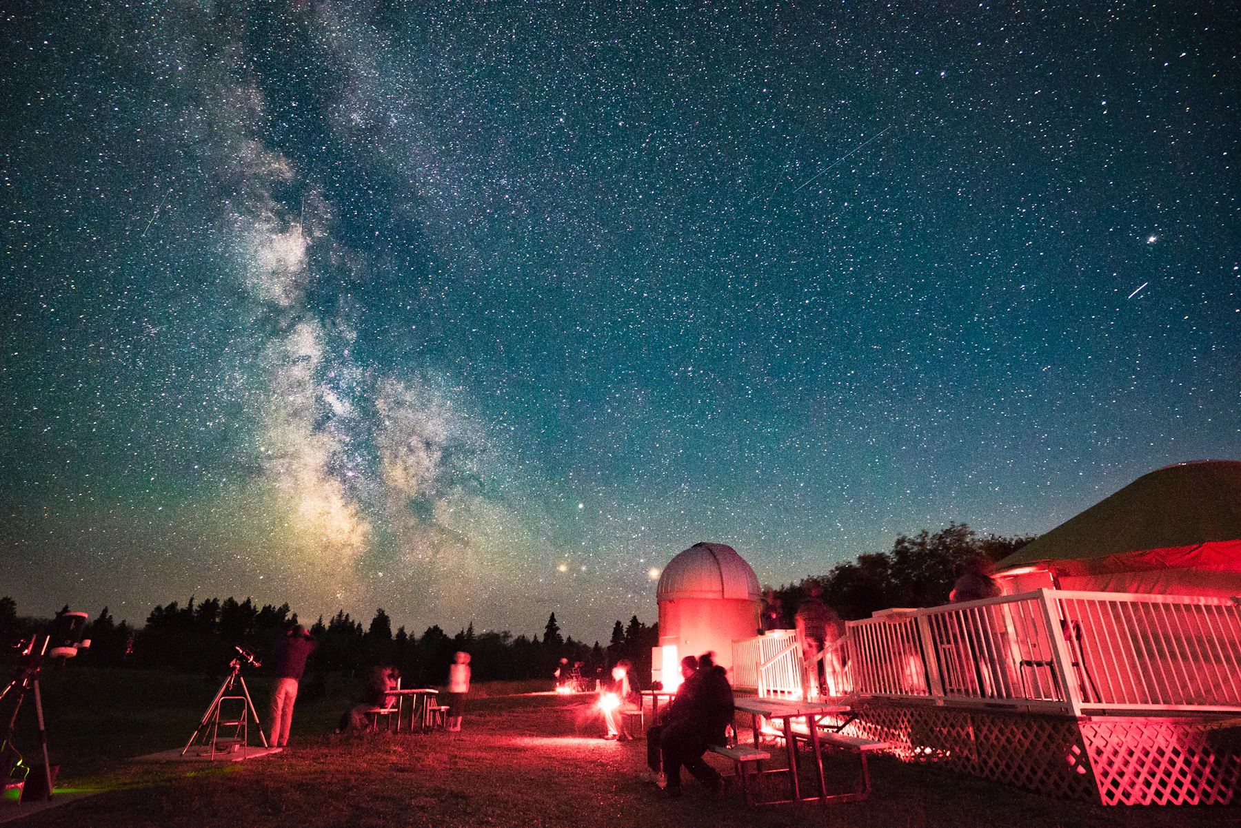 Voie lactée au-dessus d’un observatoire et de personnes observant le ciel
