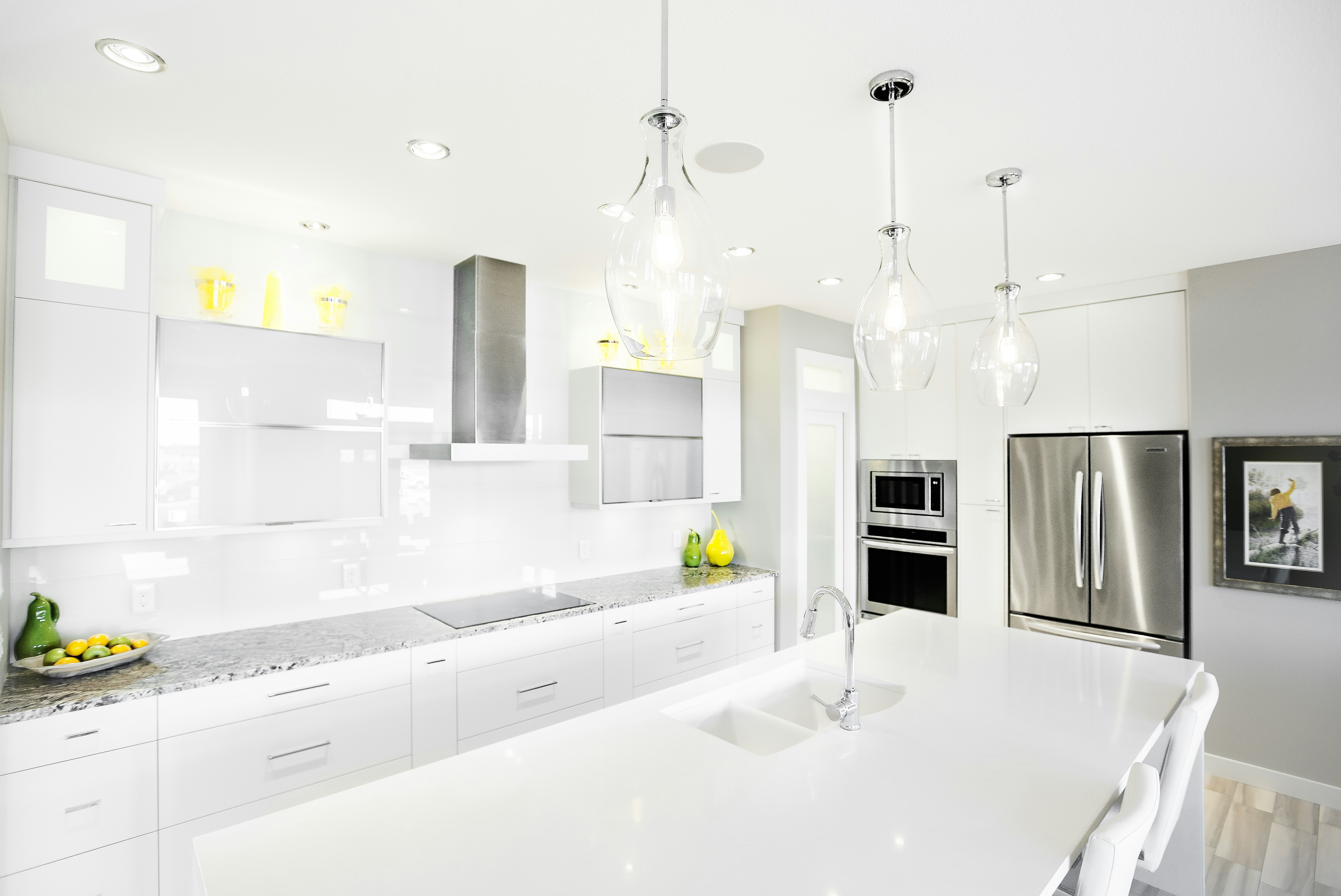 Modern white kitchen with island and stainless steel appliances.