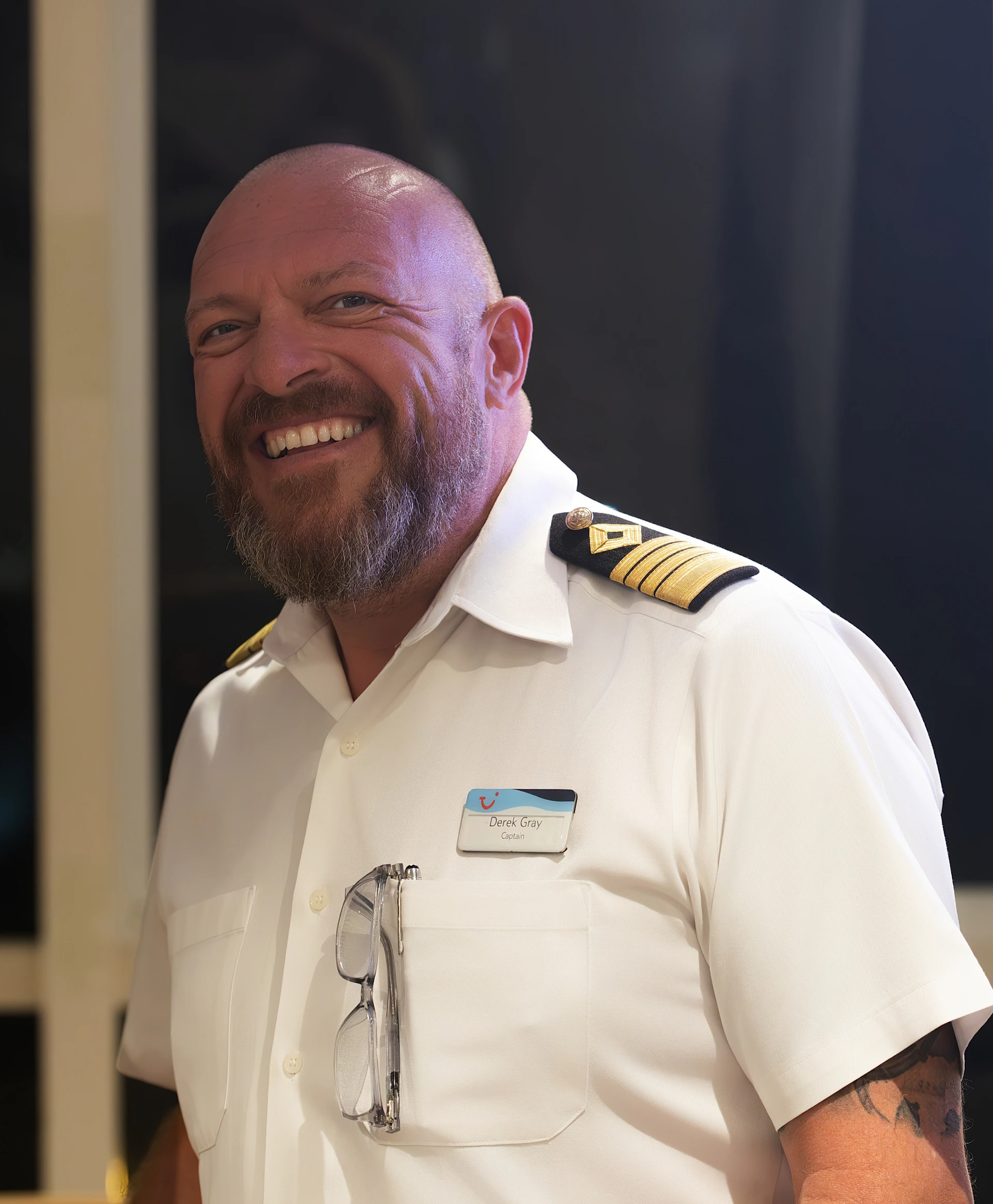 A smiling man wearing a white uniform with epaulets