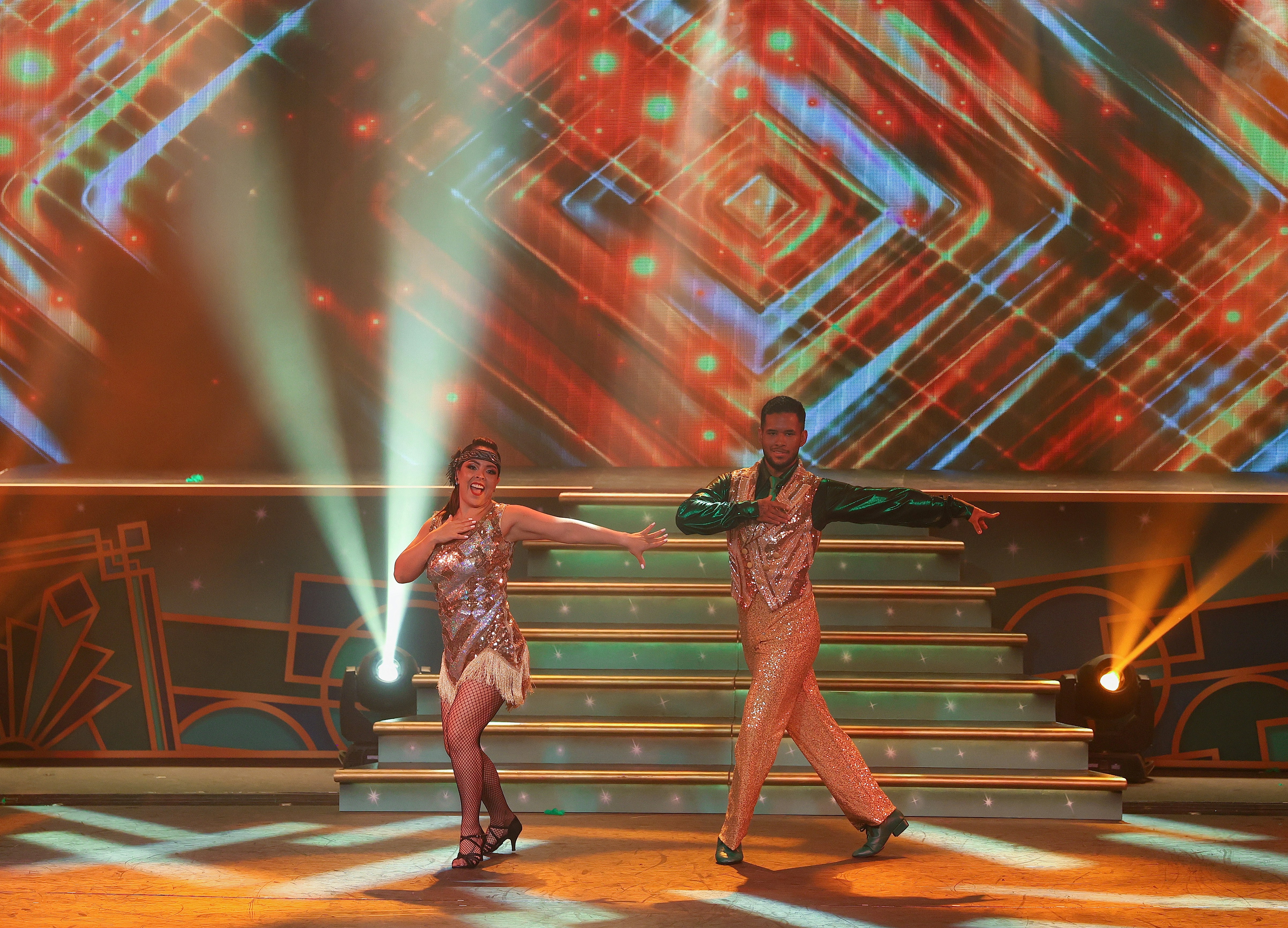 Dancers performing a routine on a vibrant, illuminated stage.