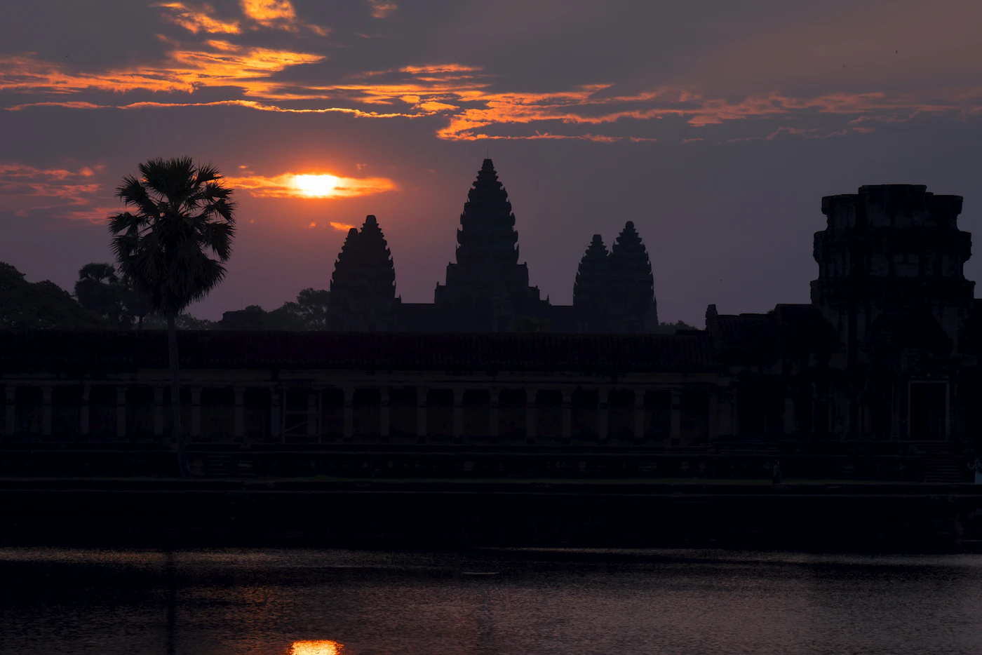 Die Tempelanlage Angkor Wat spiegelt sich bei Sonnenaufgang im Wasserbecken