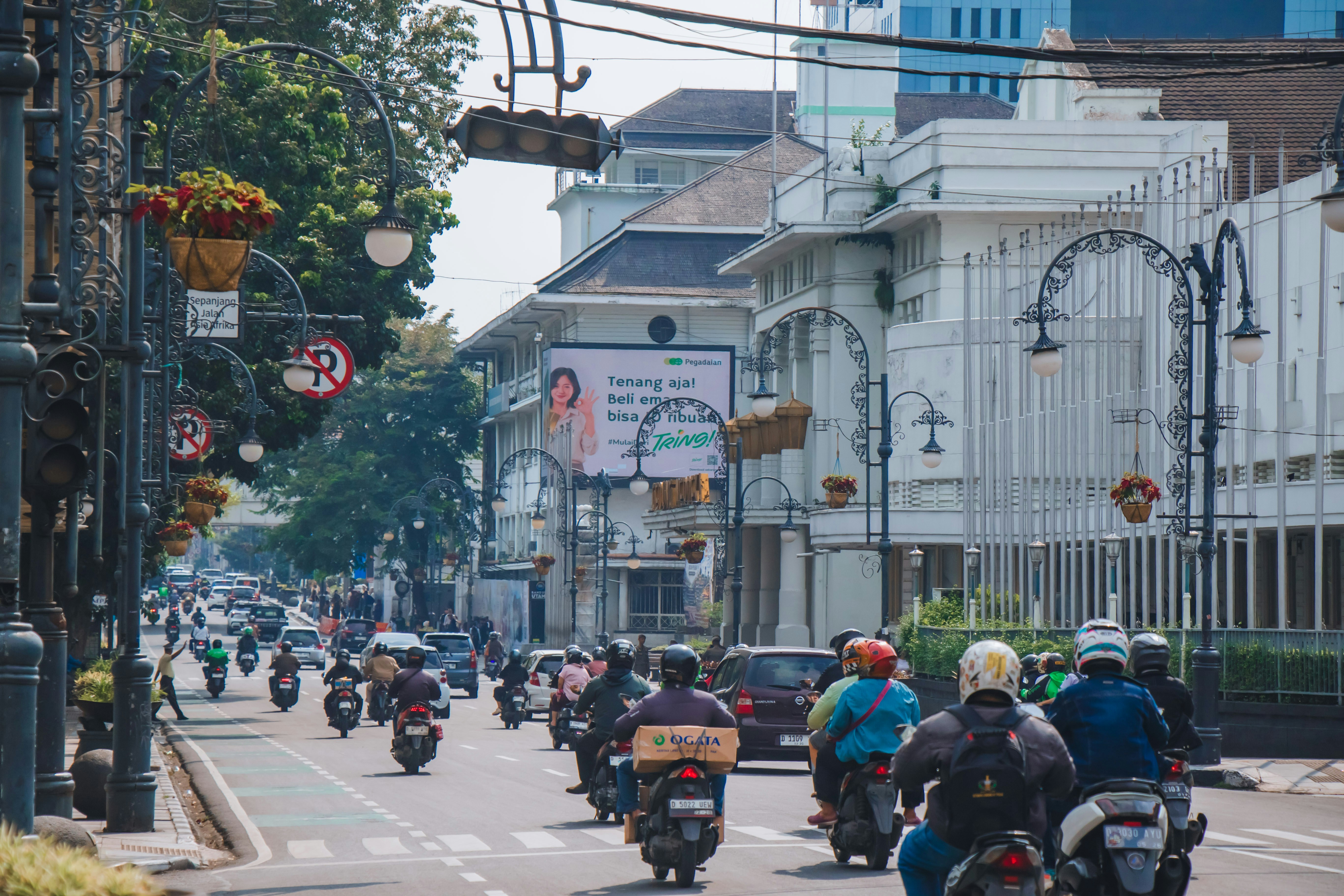 Jalan perkotaan dengan lalu lintas sepeda motor yang padat dan bangunan bersejarah.