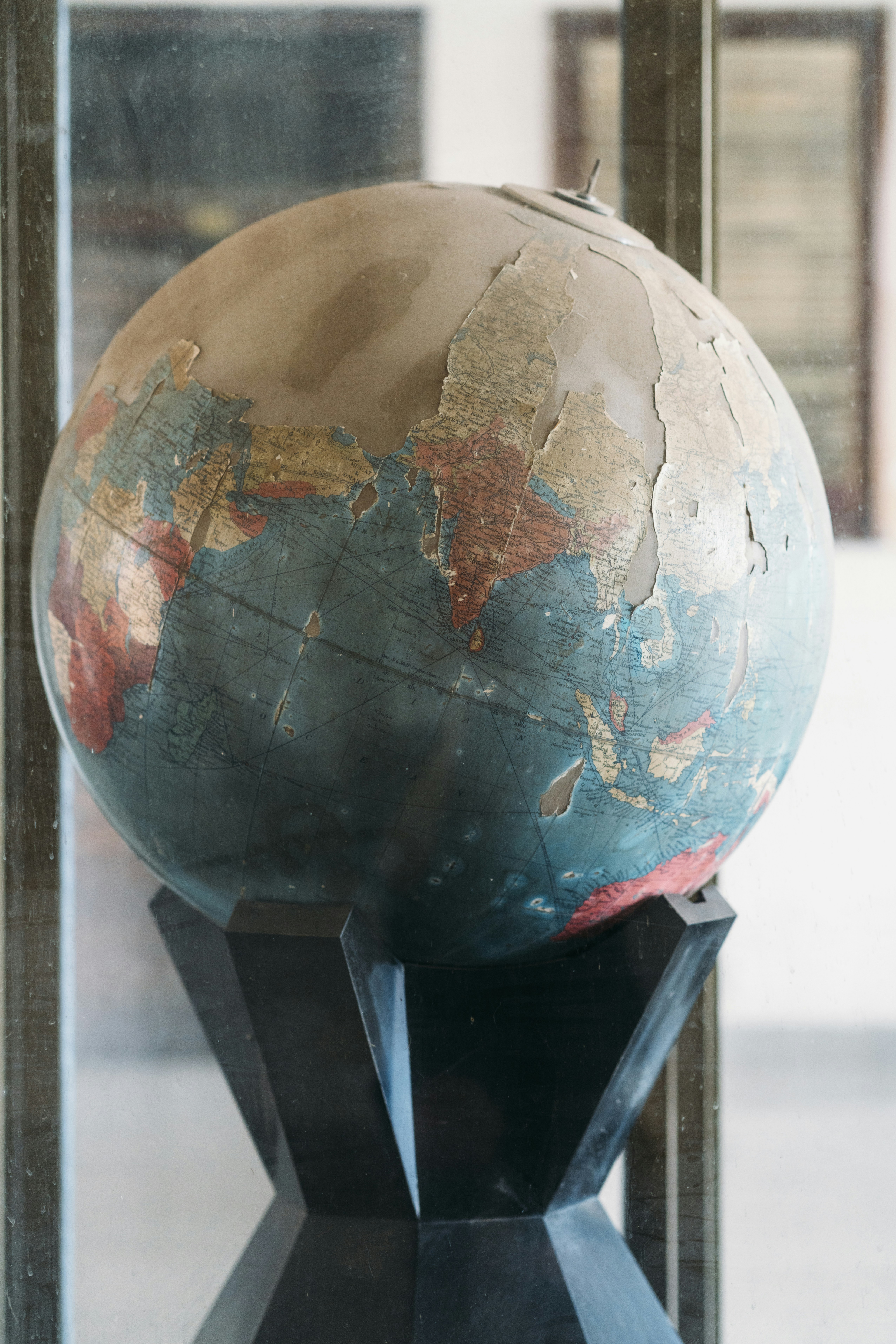 Globo desgastado con pintura descascarada sobre un soporte oscuro.
