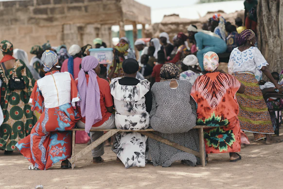 Women in colorful clothes sitting on a bench outdoors.
