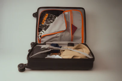 An open black suitcase packed with clothes and travel essentials
