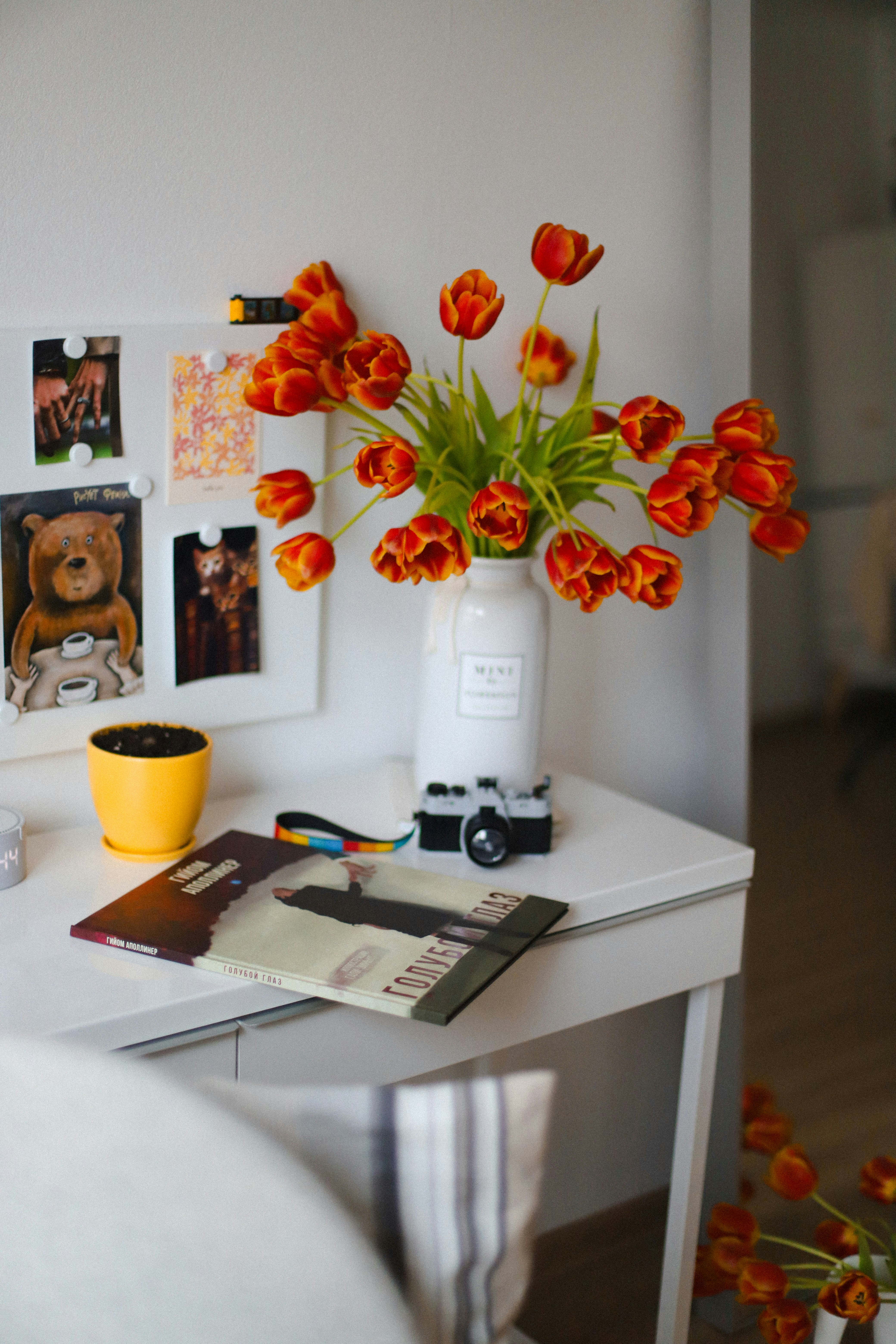 Vibrant tulips, camera, and decor on a white desk.