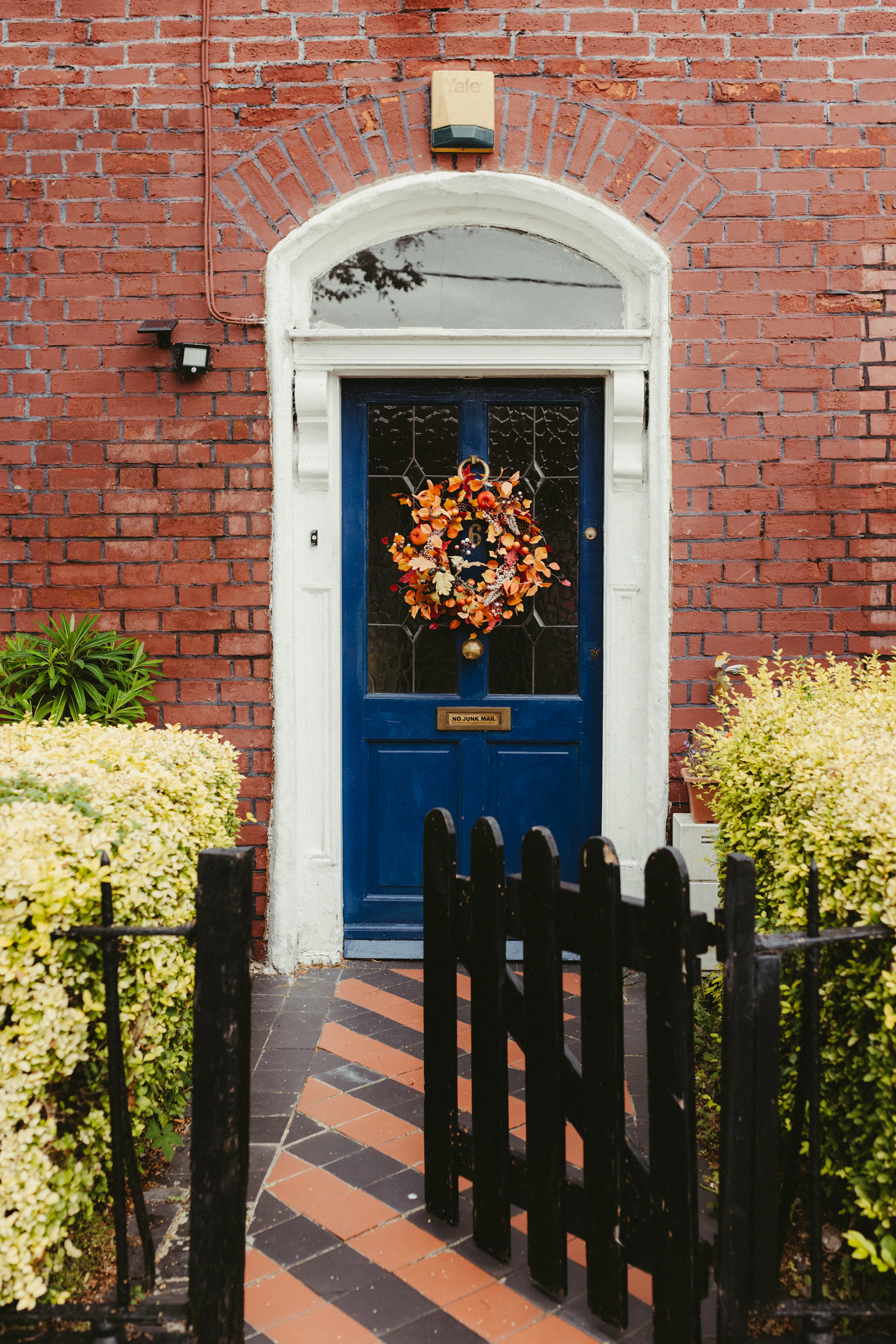 Blue front door of a brick house decorated with an autumn wreath