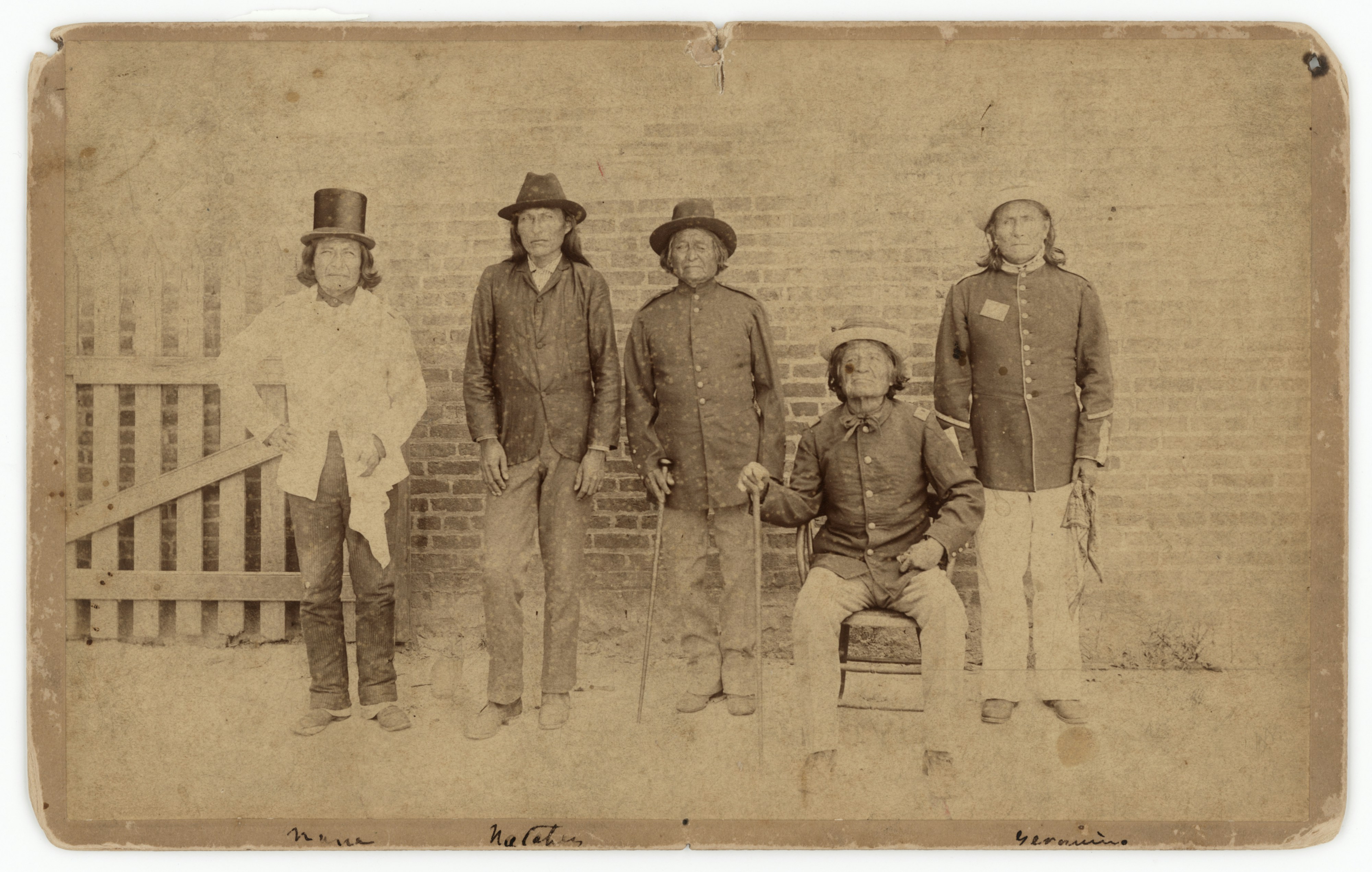 Five men in hats and period attire standing and sitting.