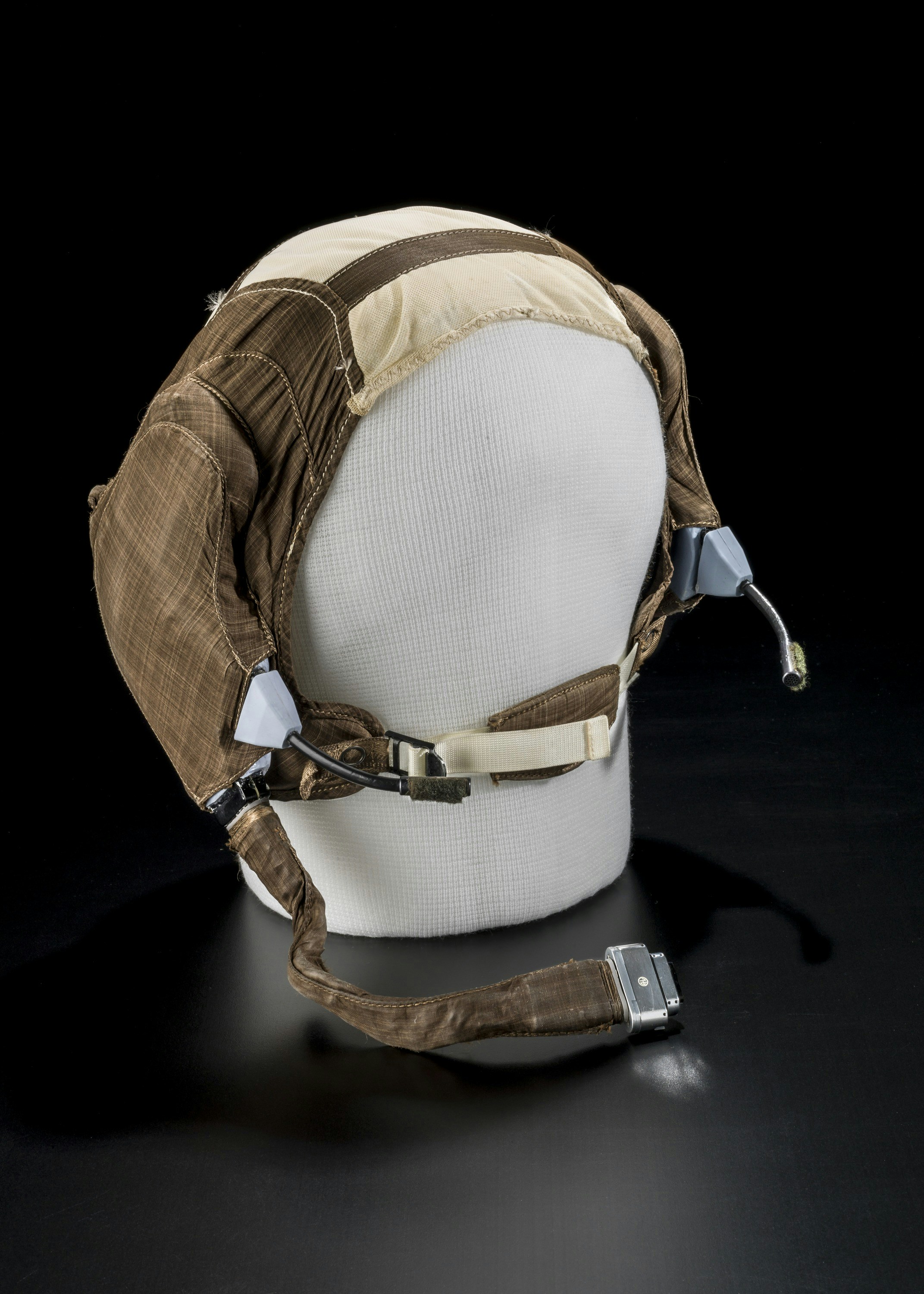 Un vecchio casco da aviatore marrone su una testa bianca di manichino.