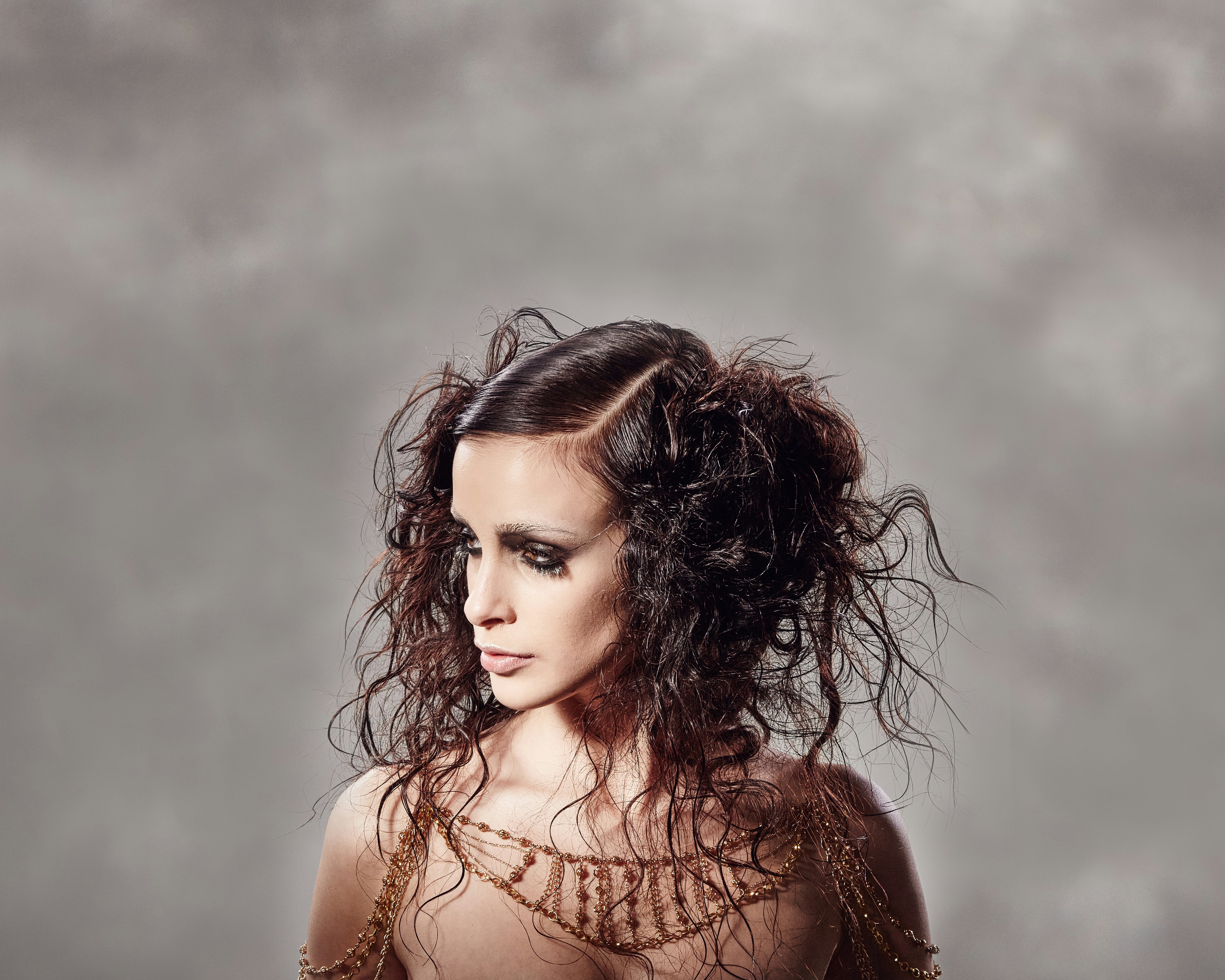 Mulher com cabelo elaborado e maquiagem contra um fundo nublado.