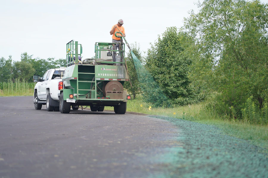 Worker applying hydroseed along a road verge