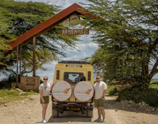Two people with a safari vehicle under a serengeti archway.