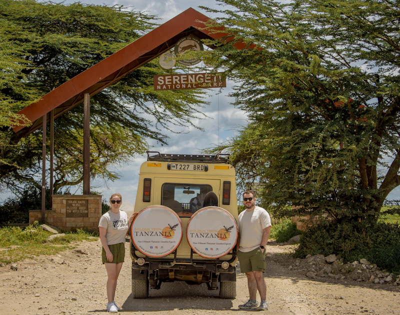 A safari vehicle at the Serengeti National Park entrance archway, Tanzania