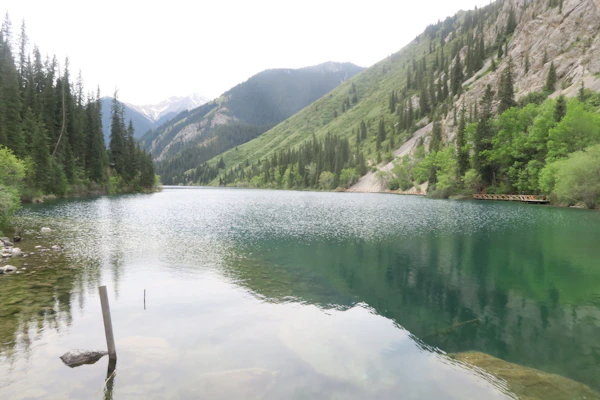 Serene blue-green lake surrounded by lush green mountains in Kazakhstan