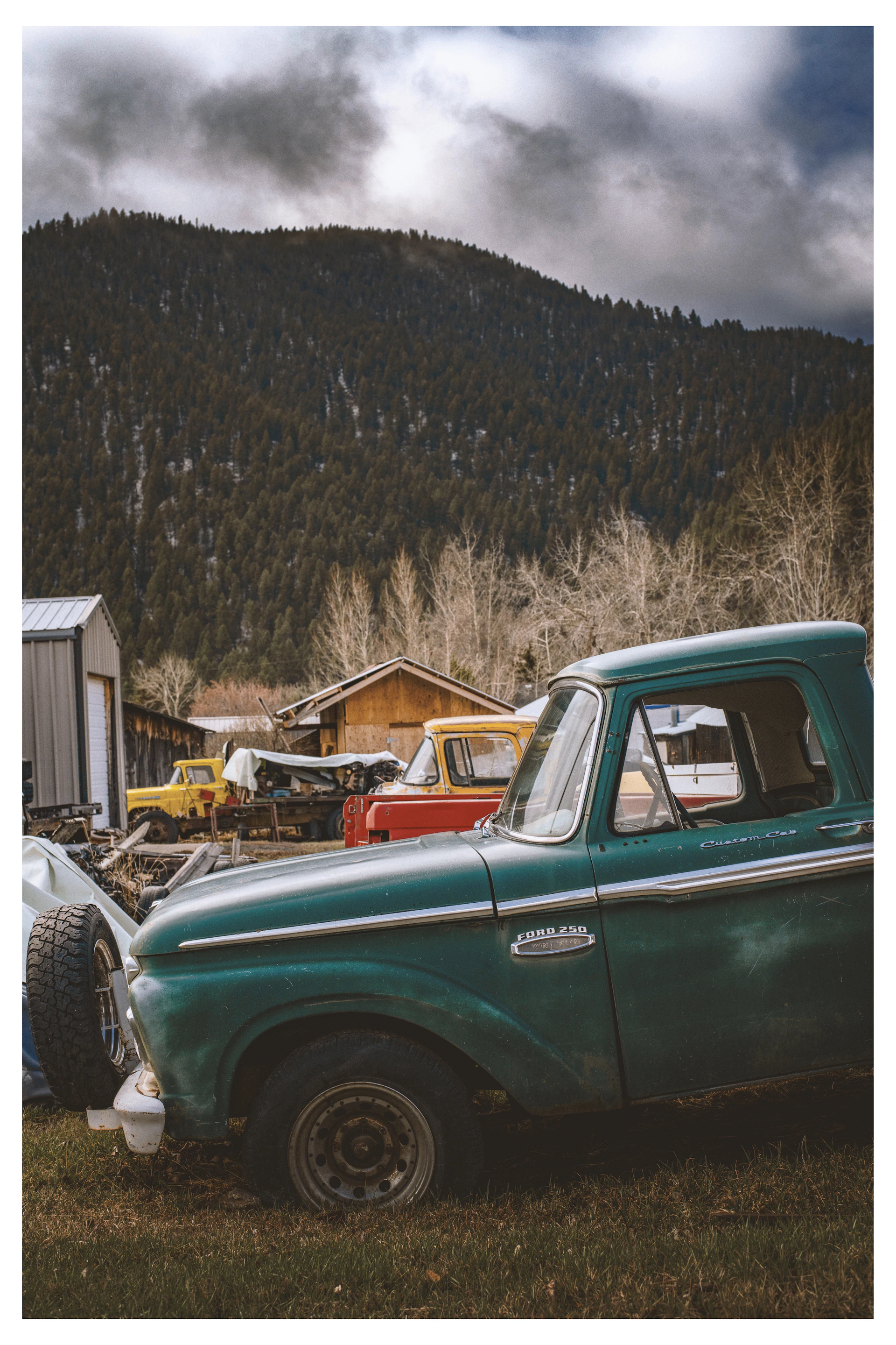 Green vintage truck with mountains and buildings in background