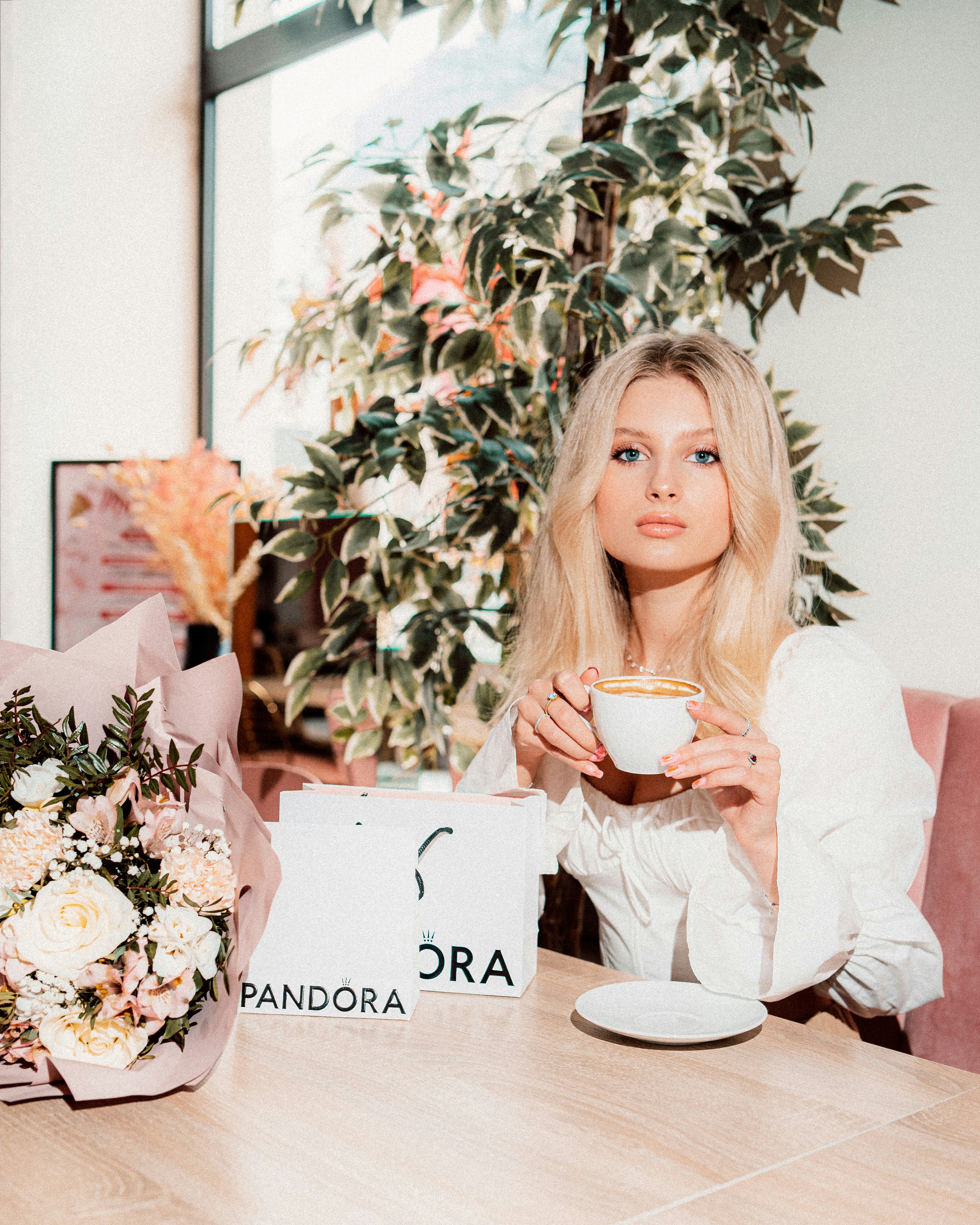 Young woman sips tea with pandora bags and flowers