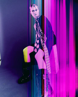Model in black with neon accent against vibrant light streaks