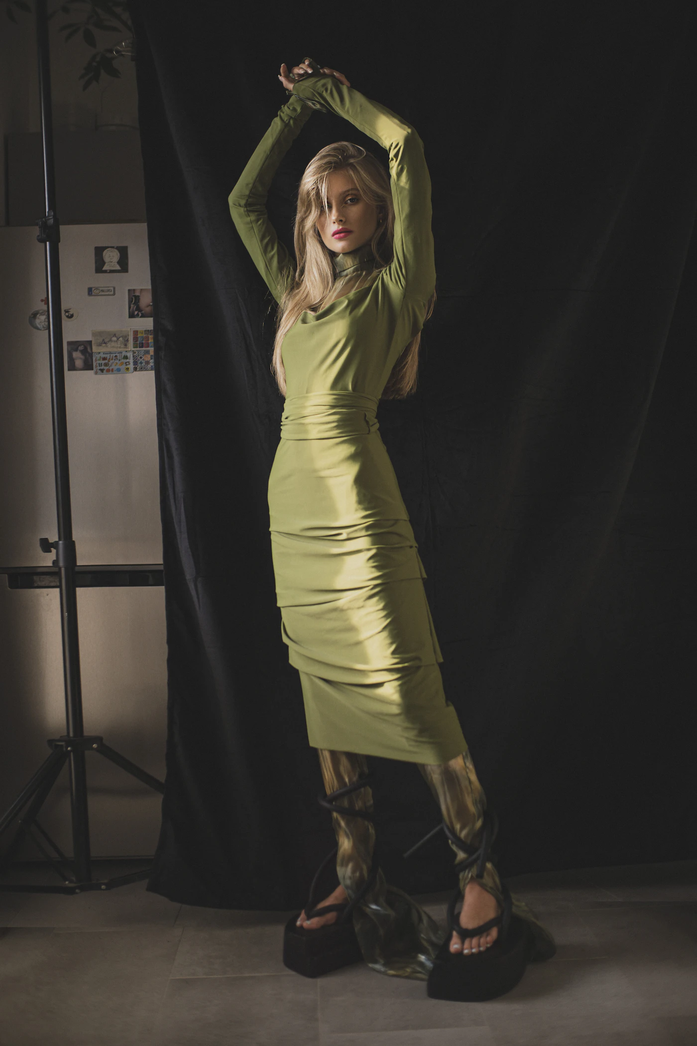 Green satin dress against a dark studio backdrop