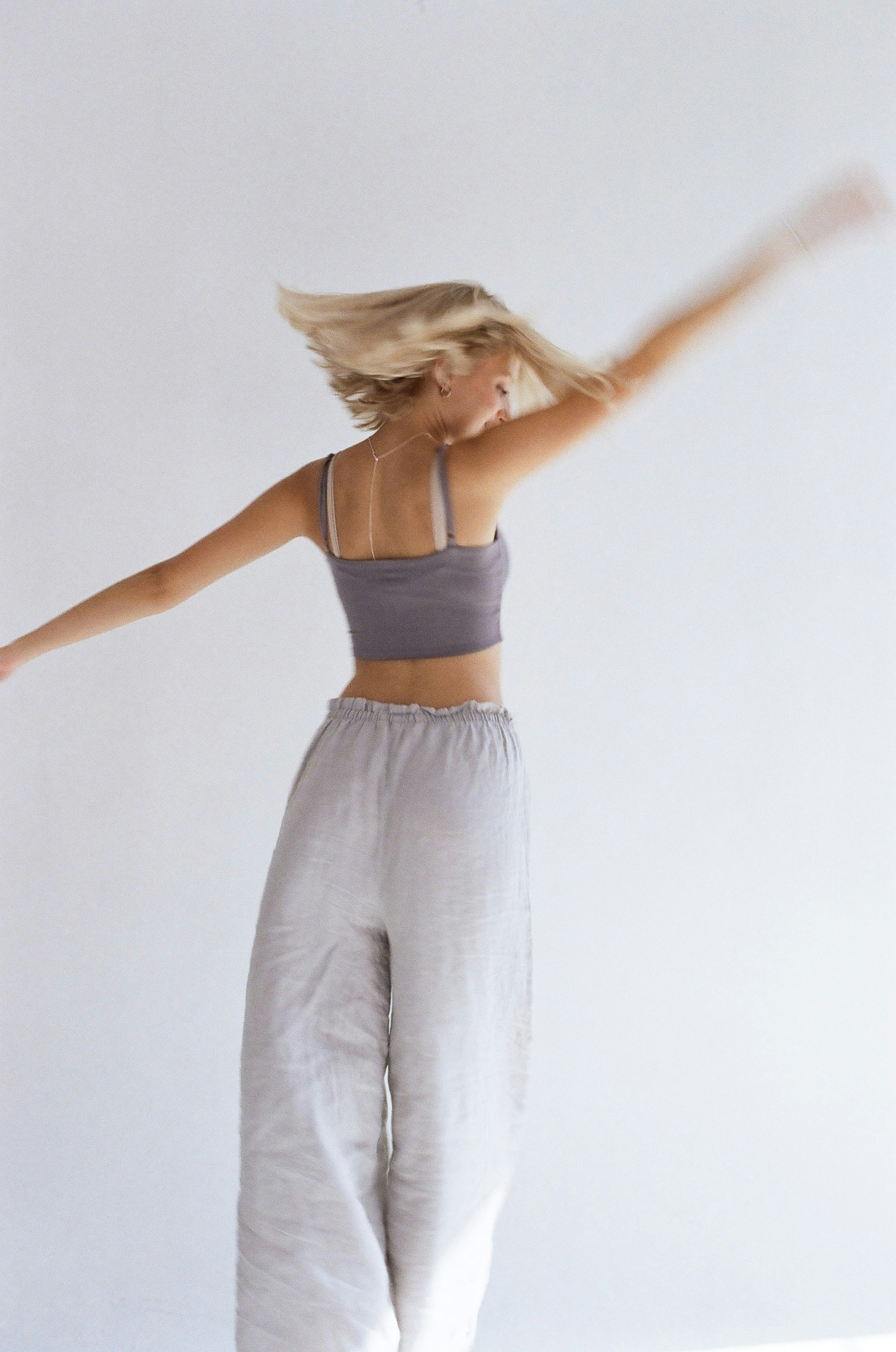 Femme blonde tournant avec des cheveux flous sur fond blanc.