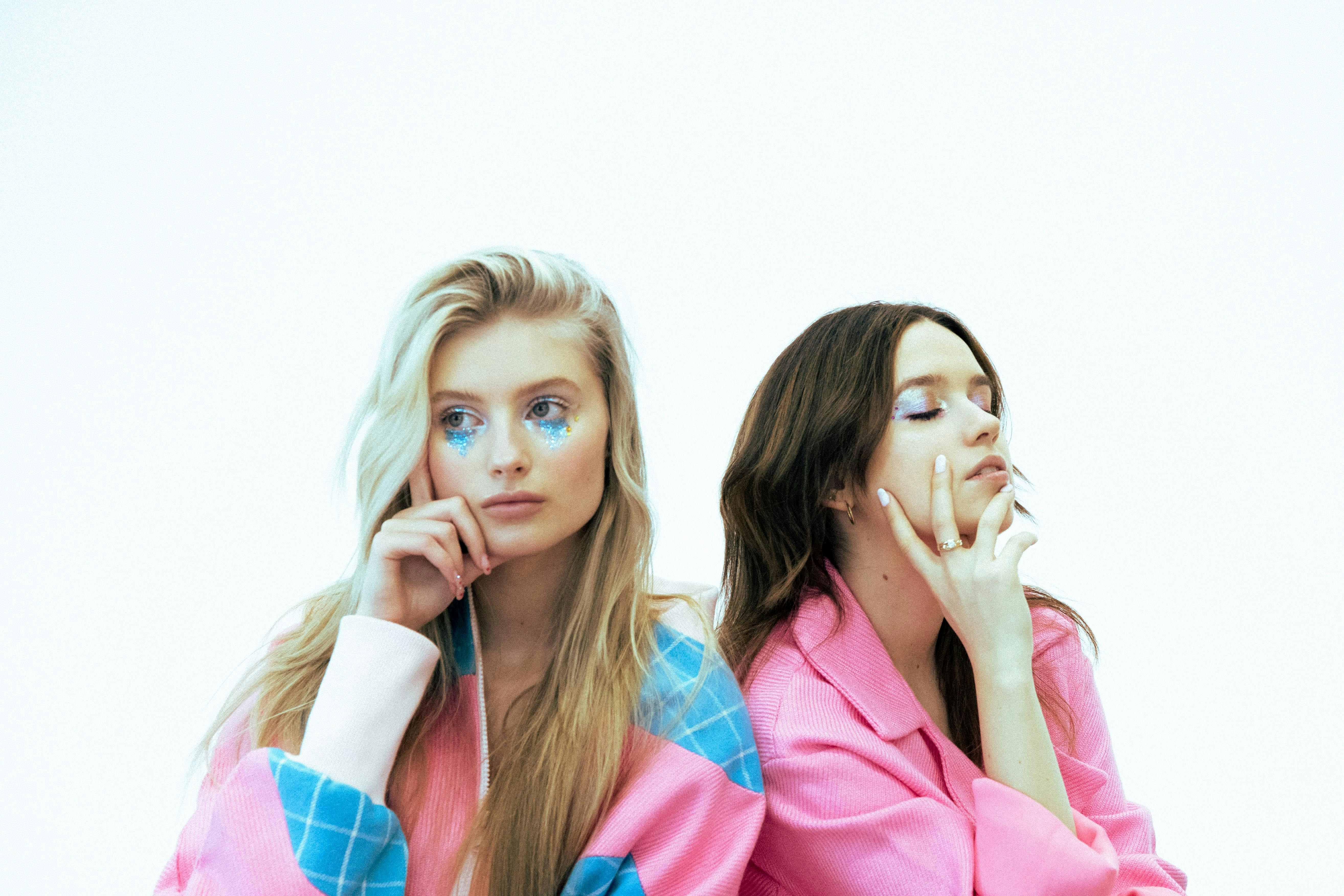 Two young women with thoughtful expressions and pink attire.