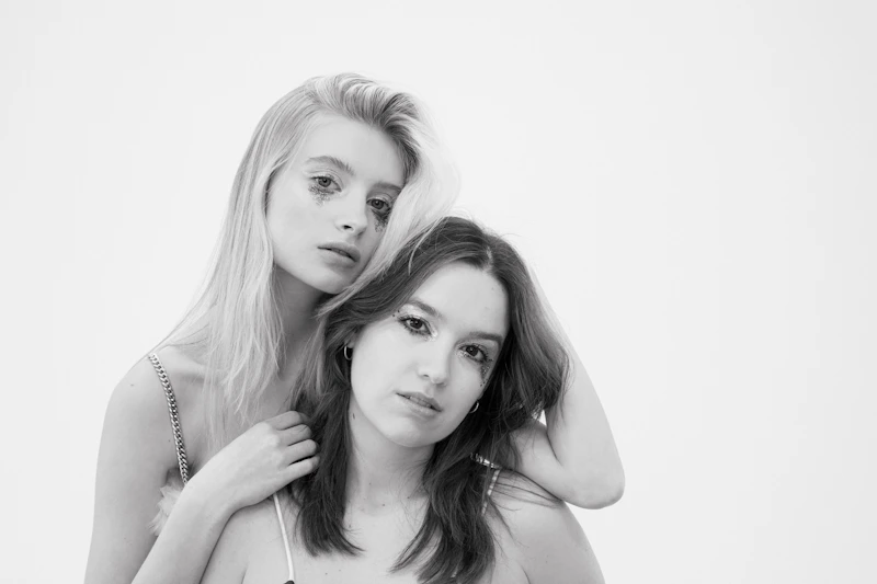 two young women posing together in black and white