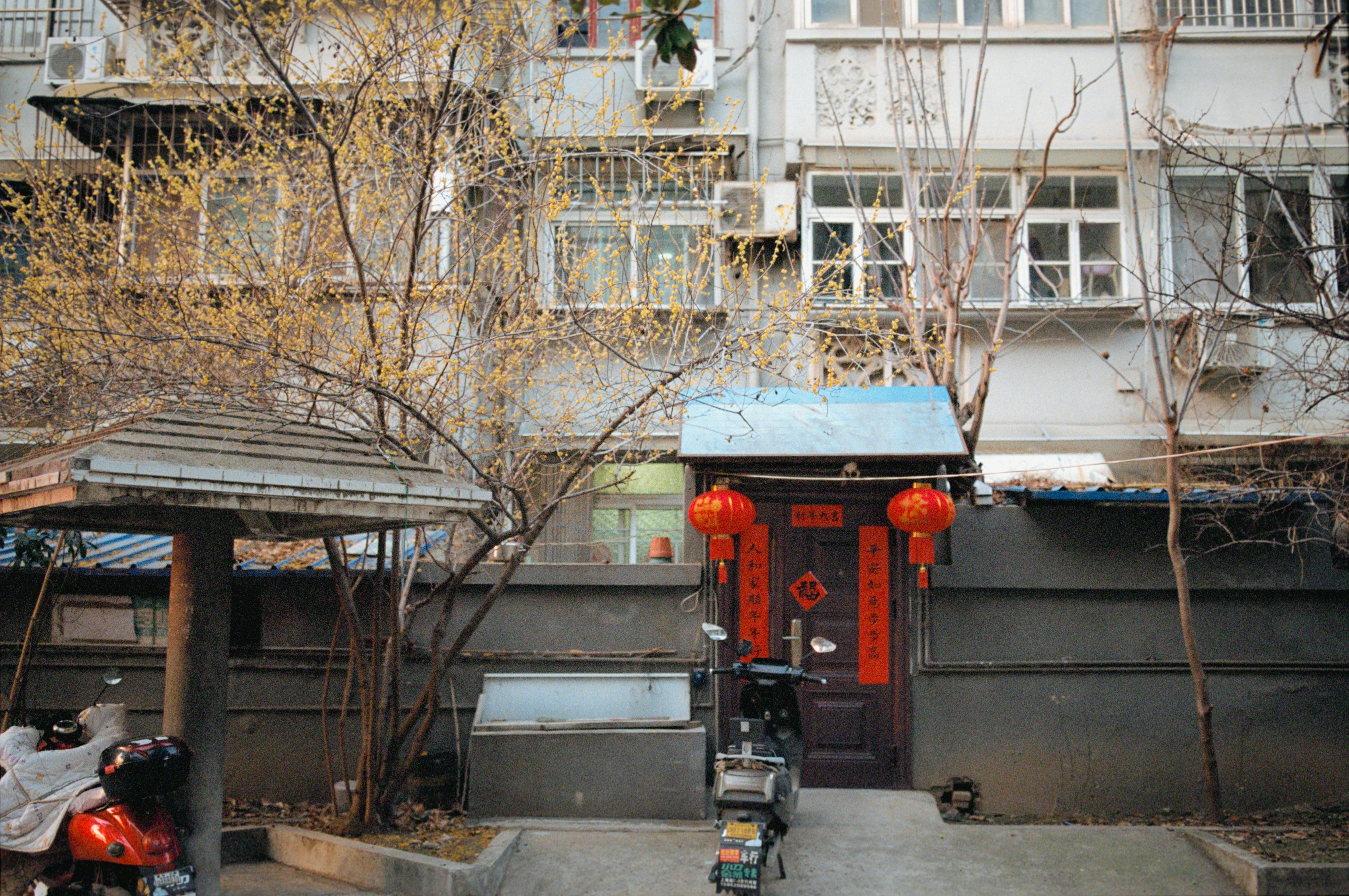 Red decorated small building with motorcycle in front of apartments.