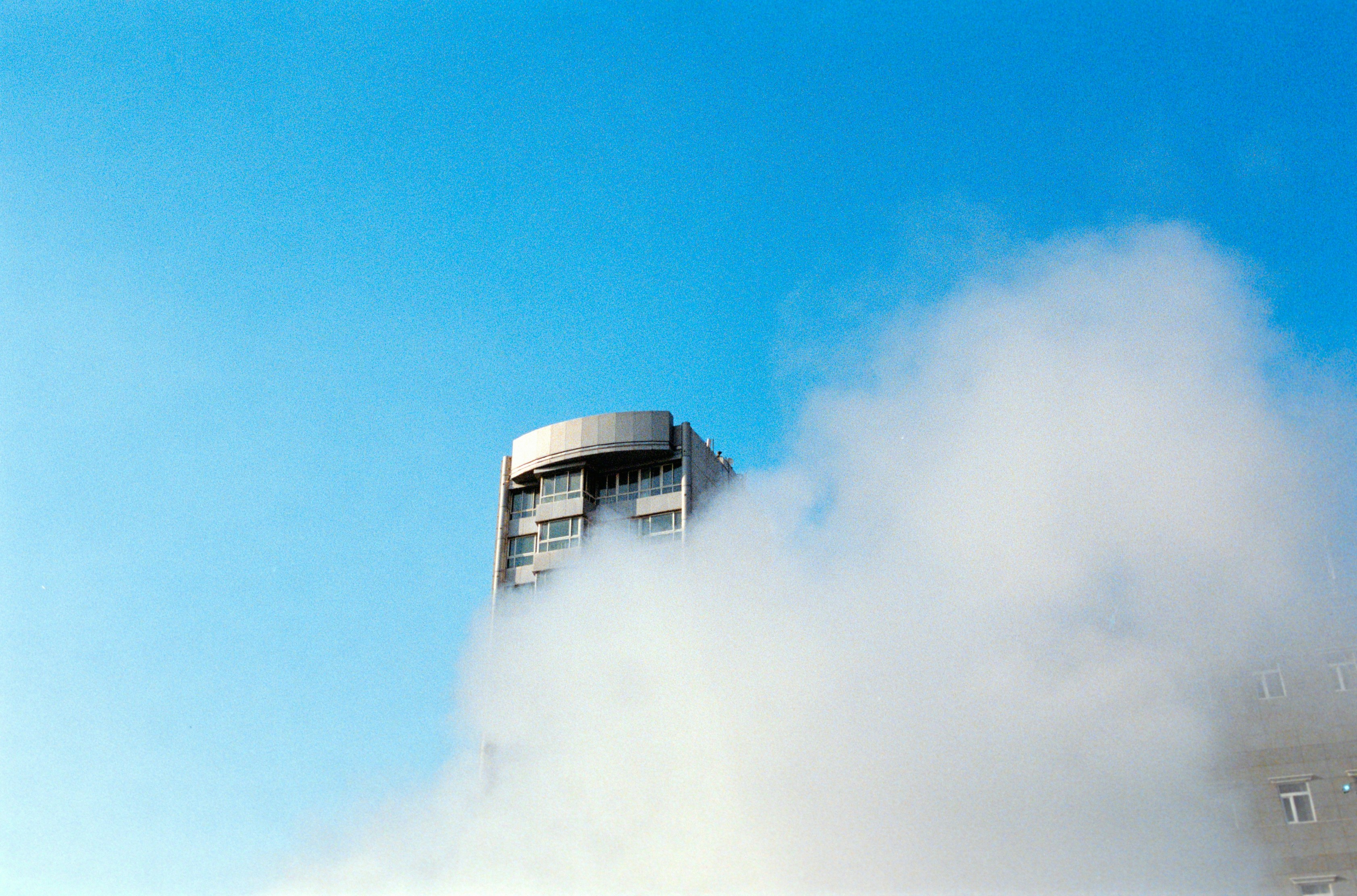 Building shrouded in white vapor under a clear blue sky.