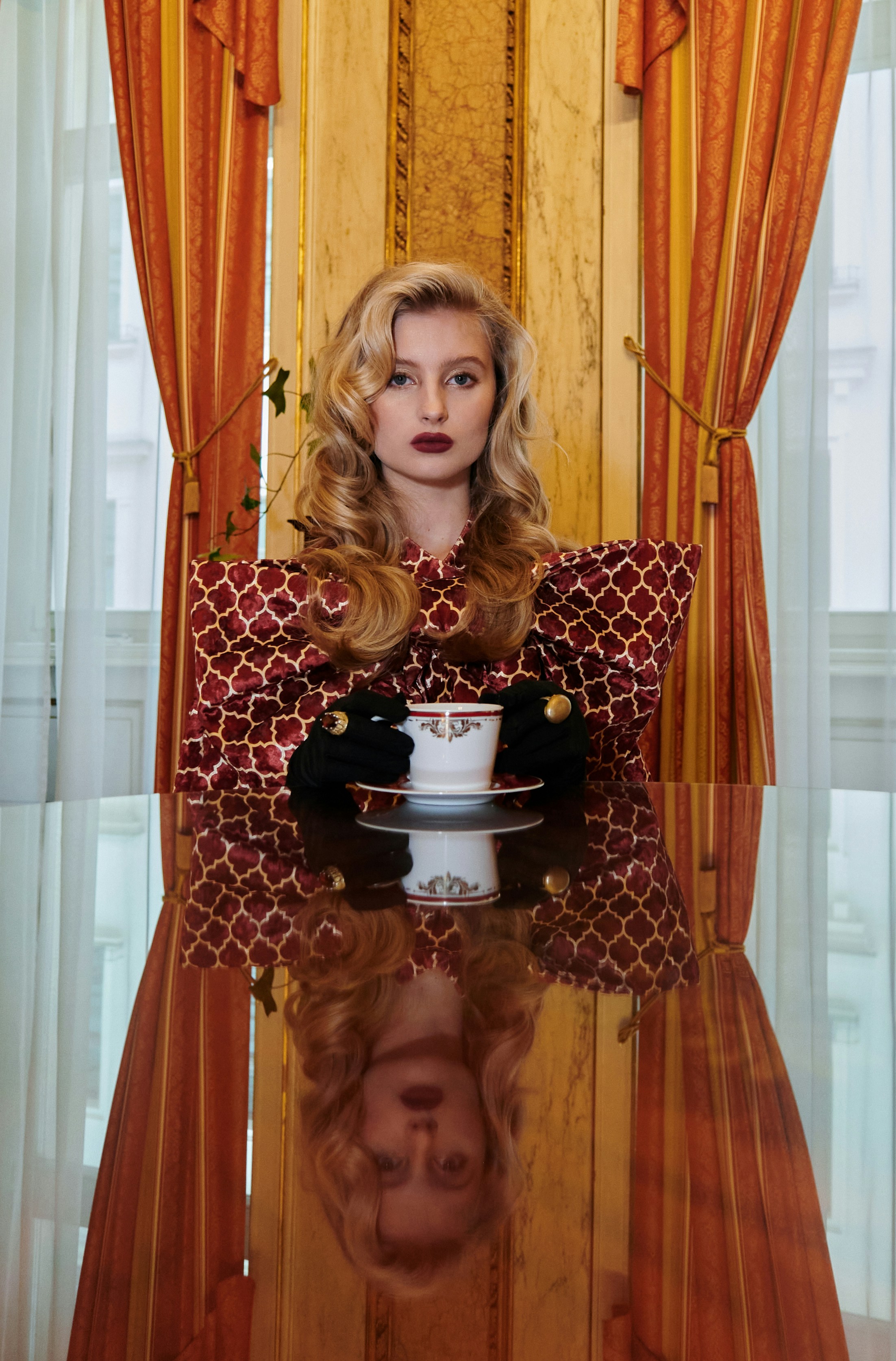 Elegant woman with teacup reflected on a shiny table